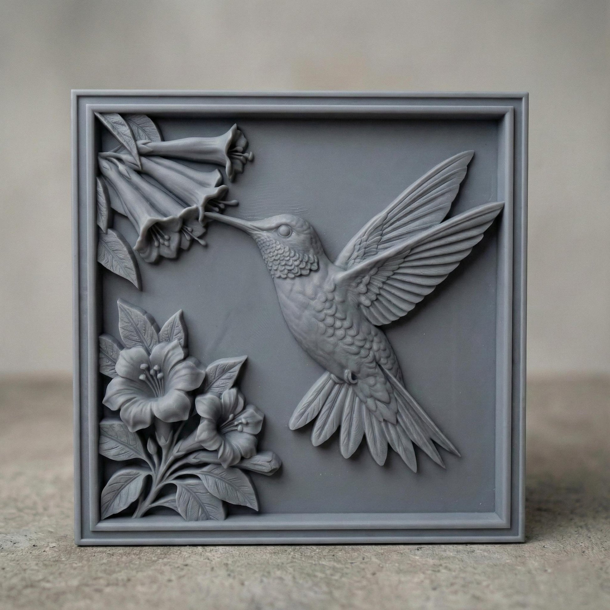 Intricate hummingbird and flower bas relief STL featuring a hummingbird in flight reaching toward trumpet-shaped blossoms, framed within a decorative rectangular border. The design includes layered feathers, detailed floral petals, and carved leaves, ideal for CNC wood carving, 3D printing, or framed wall art panels. Perfect for botanical décor, nature-inspired interiors, and elegant handcrafted relief projects.