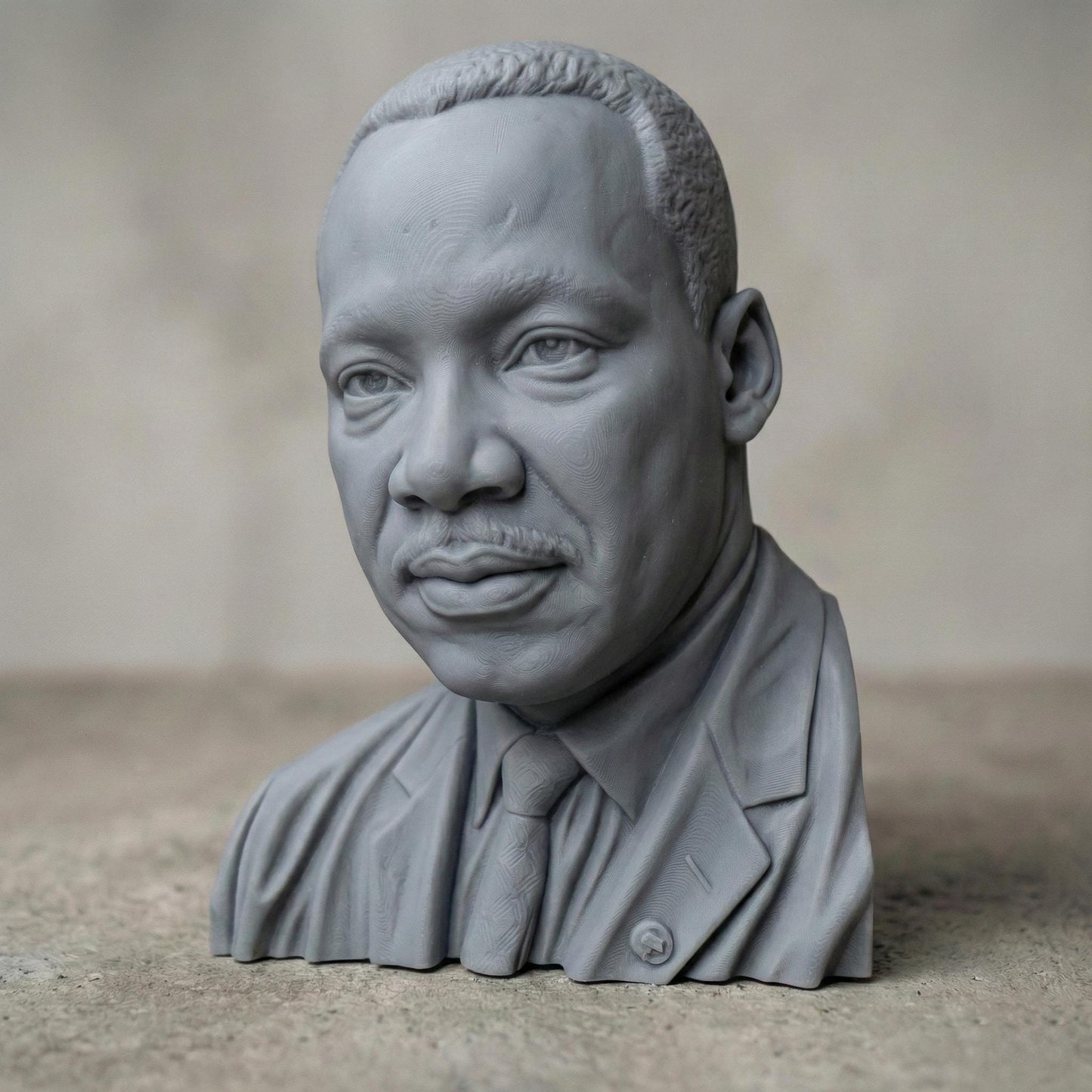 Highly detailed 3D portrait bust of Martin Luther King Jr., depicted with a calm, thoughtful expression and formal suit and tie. Rendered in a realistic wood-carved style, the sculpture emphasizes facial depth, historical dignity, and symbolic leadership. Ideal for Martin Luther King Jr. Day displays, educational settings, memorial art, CNC carving, and 3D printing projects honoring civil rights history.