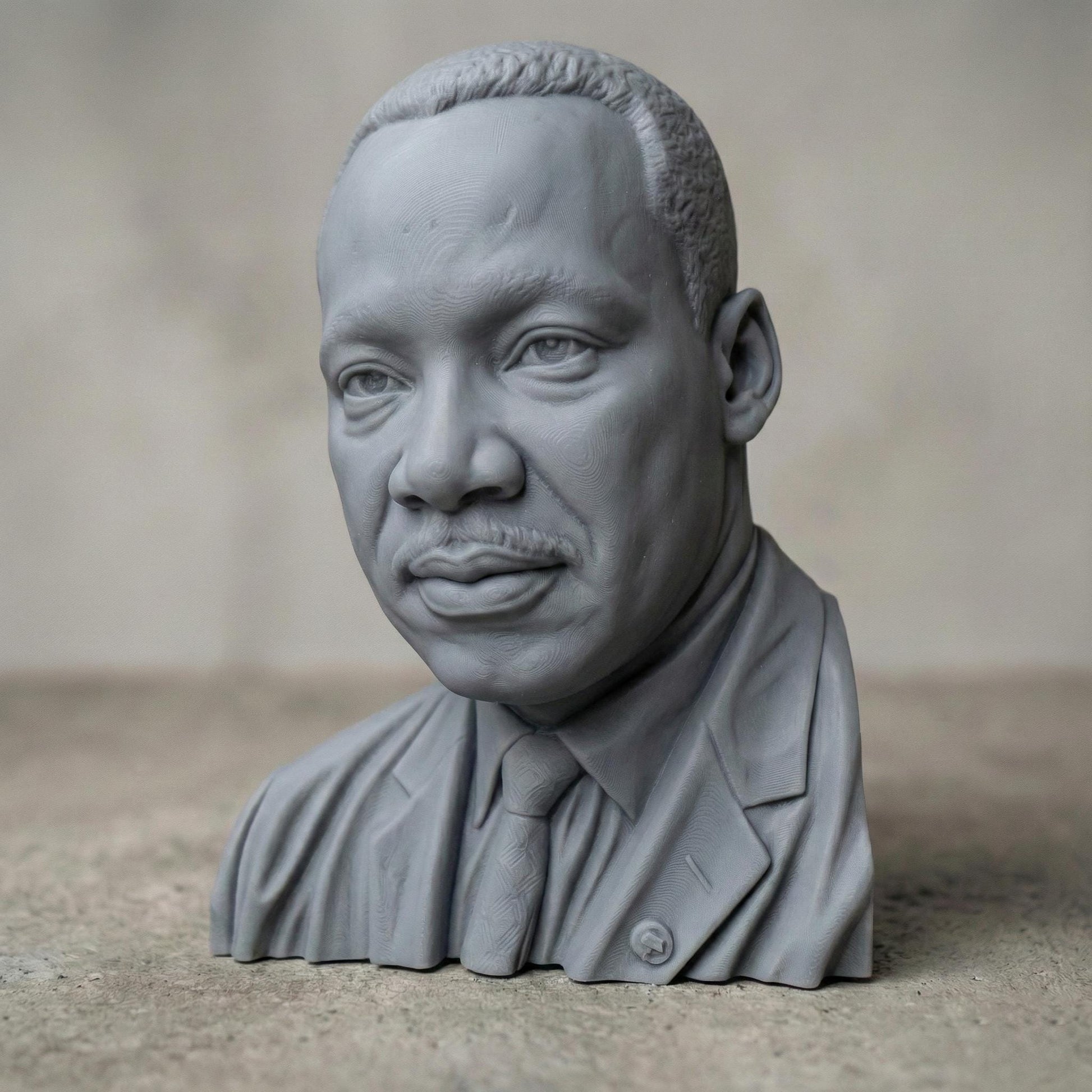 Highly detailed 3D portrait bust of Martin Luther King Jr., depicted with a calm, thoughtful expression and formal suit and tie. Rendered in a realistic wood-carved style, the sculpture emphasizes facial depth, historical dignity, and symbolic leadership. Ideal for Martin Luther King Jr. Day displays, educational settings, memorial art, CNC carving, and 3D printing projects honoring civil rights history.
