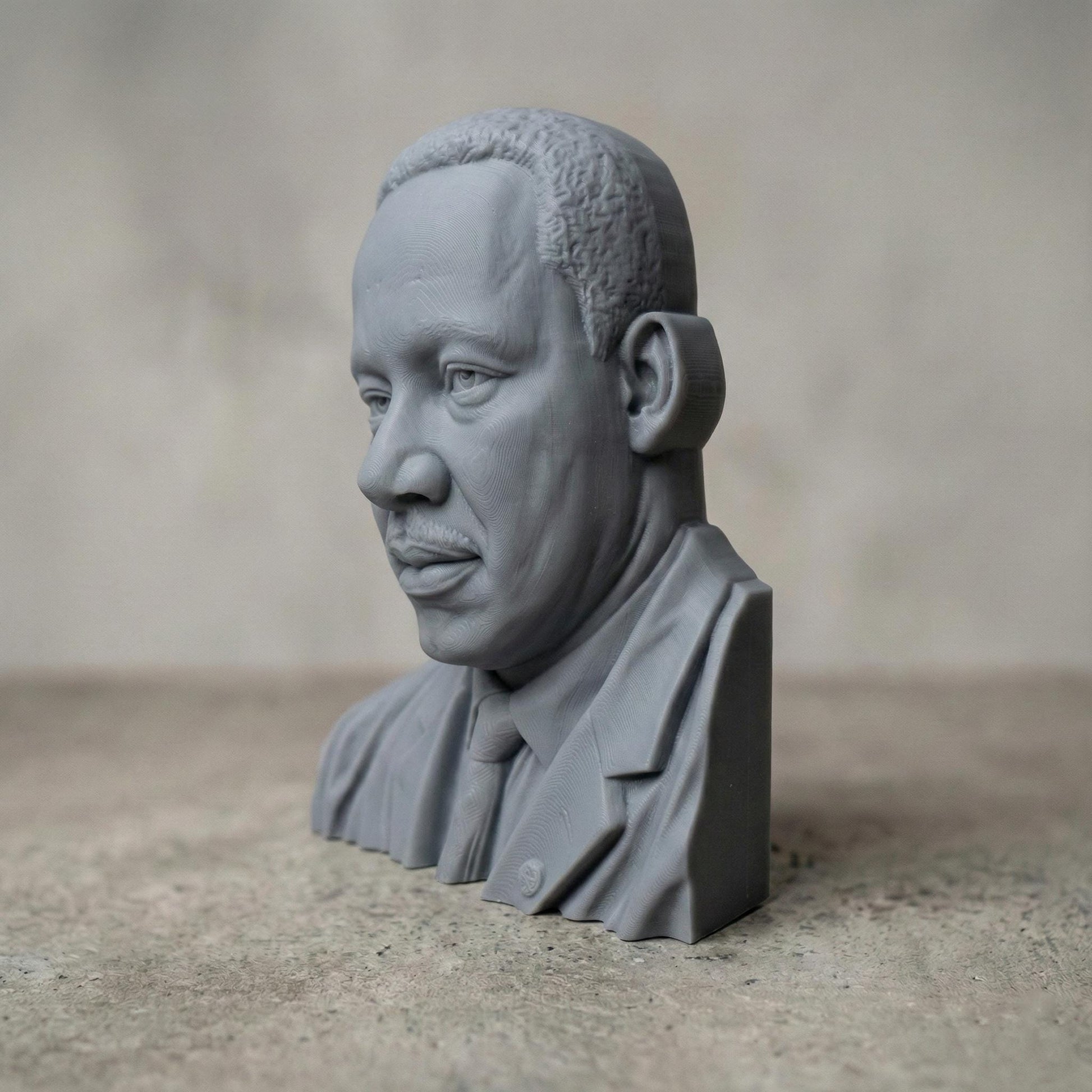 Highly detailed 3D portrait bust of Martin Luther King Jr., depicted with a calm, thoughtful expression and formal suit and tie. Rendered in a realistic wood-carved style, the sculpture emphasizes facial depth, historical dignity, and symbolic leadership. Ideal for Martin Luther King Jr. Day displays, educational settings, memorial art, CNC carving, and 3D printing projects honoring civil rights history.