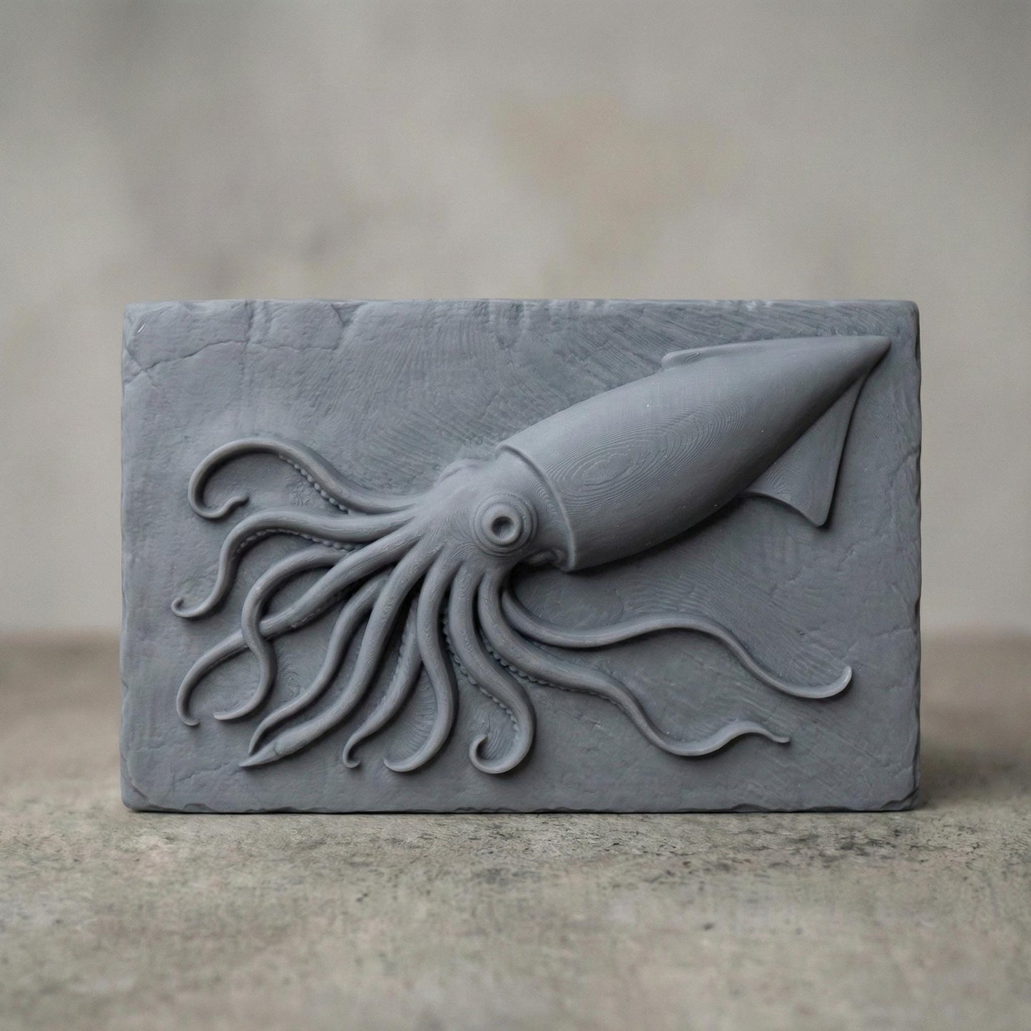 A highly detailed 3D bas relief carving of a squid crafted in a rich reddish-brown wood tone. The squid is positioned diagonally on a rectangular slab with its long tentacles dynamically flowing in various directions, creating a sense of motion. Each tentacle is intricately rendered with natural curvature and suction cups, while the squid’s large eye and streamlined body give it a lifelike presence. The background slab has chipped, rough edges and a vertical wood grain texture.