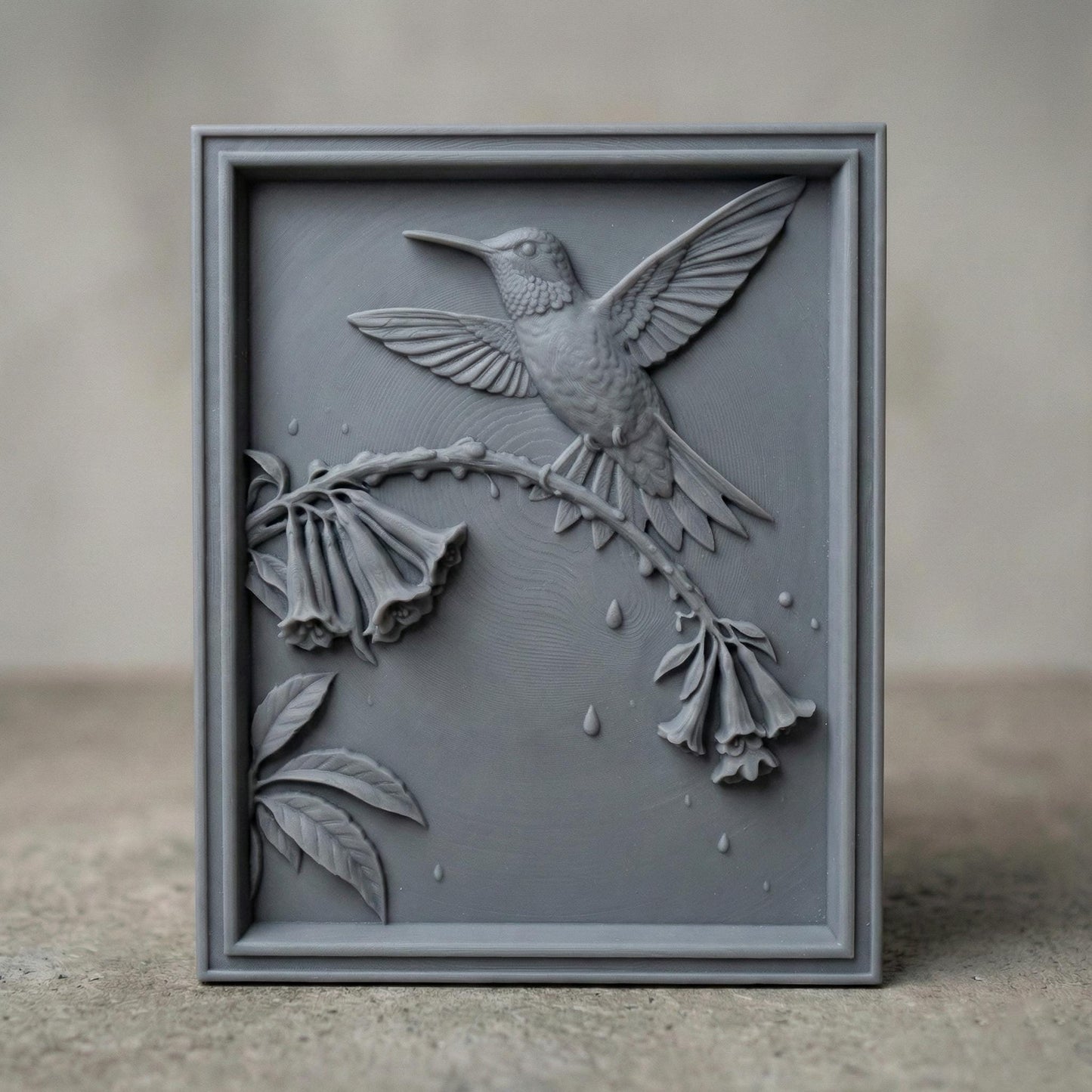Elegant hummingbird bas relief STL depicting a hummingbird in flight feeding from cascading bell-shaped flowers, carved within a refined rectangular frame. The design features flowing leaves, delicate floral textures, and detailed feathers set against a smooth wood-grain background. Ideal for CNC wood carving, 3D printing, or framed wall art panels inspired by botanical and wildlife themes.