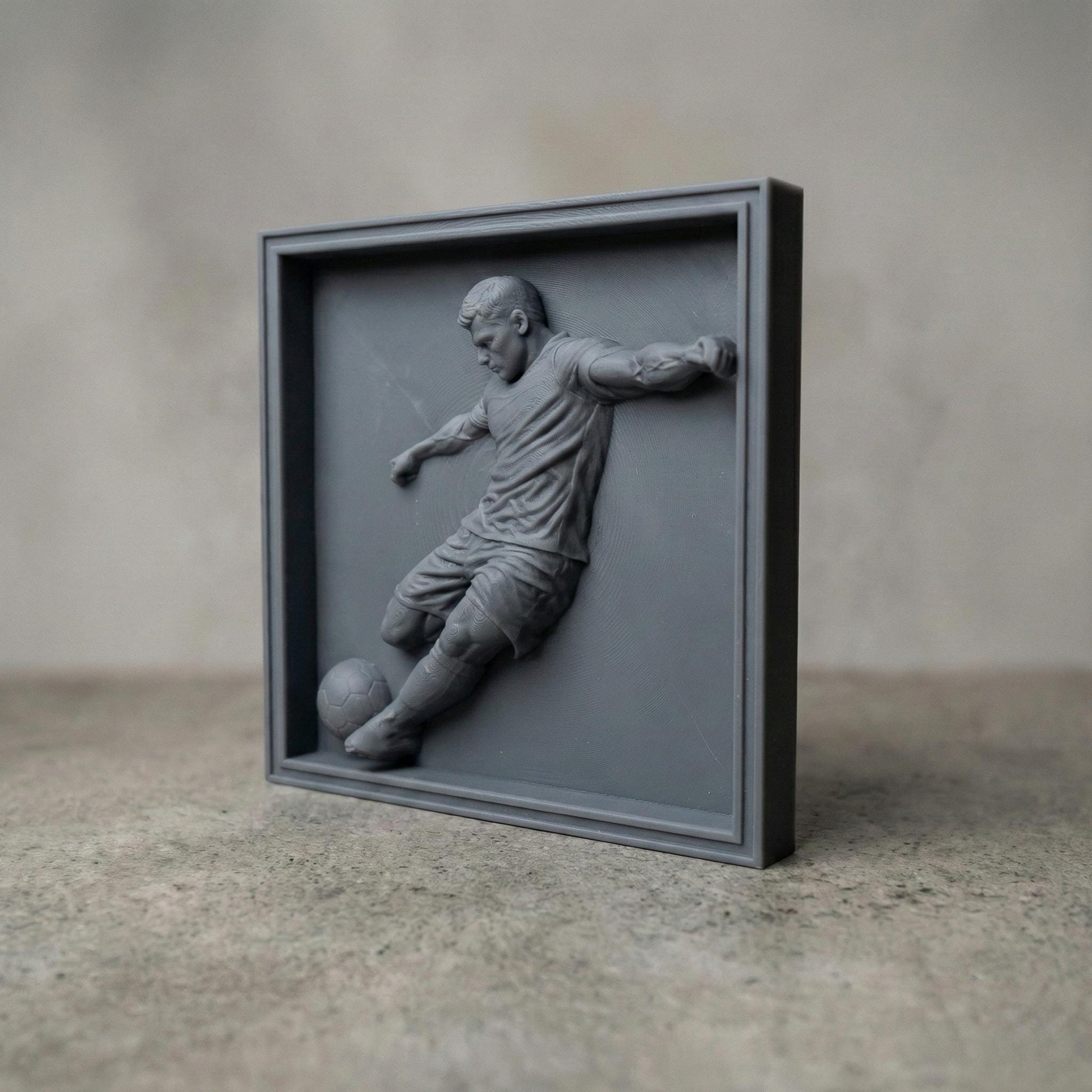 Detailed bas-relief sculpture of a soccer player captured mid-kick, shown as a realistic carved wooden relief with dynamic motion, muscular anatomy, flowing clothing folds, and a soccer ball at the foot. The design features deep relief depth, clean contours, and smooth transitions ideal for CNC carving, 3D printing, or router engraving as decorative sports wall art.