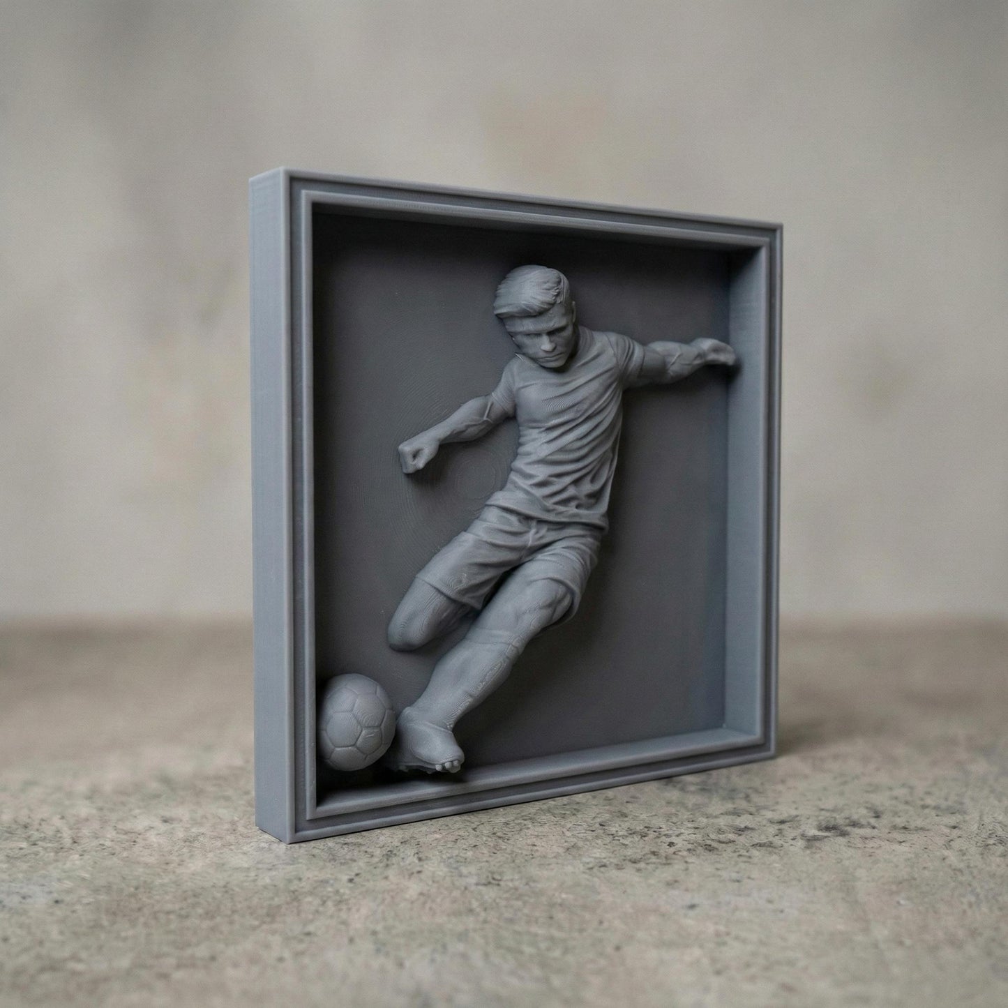 Detailed bas-relief sculpture of a soccer player captured mid-kick, shown as a realistic carved wooden relief with dynamic motion, muscular anatomy, flowing clothing folds, and a soccer ball at the foot. The design features deep relief depth, clean contours, and smooth transitions ideal for CNC carving, 3D printing, or router engraving as decorative sports wall art.