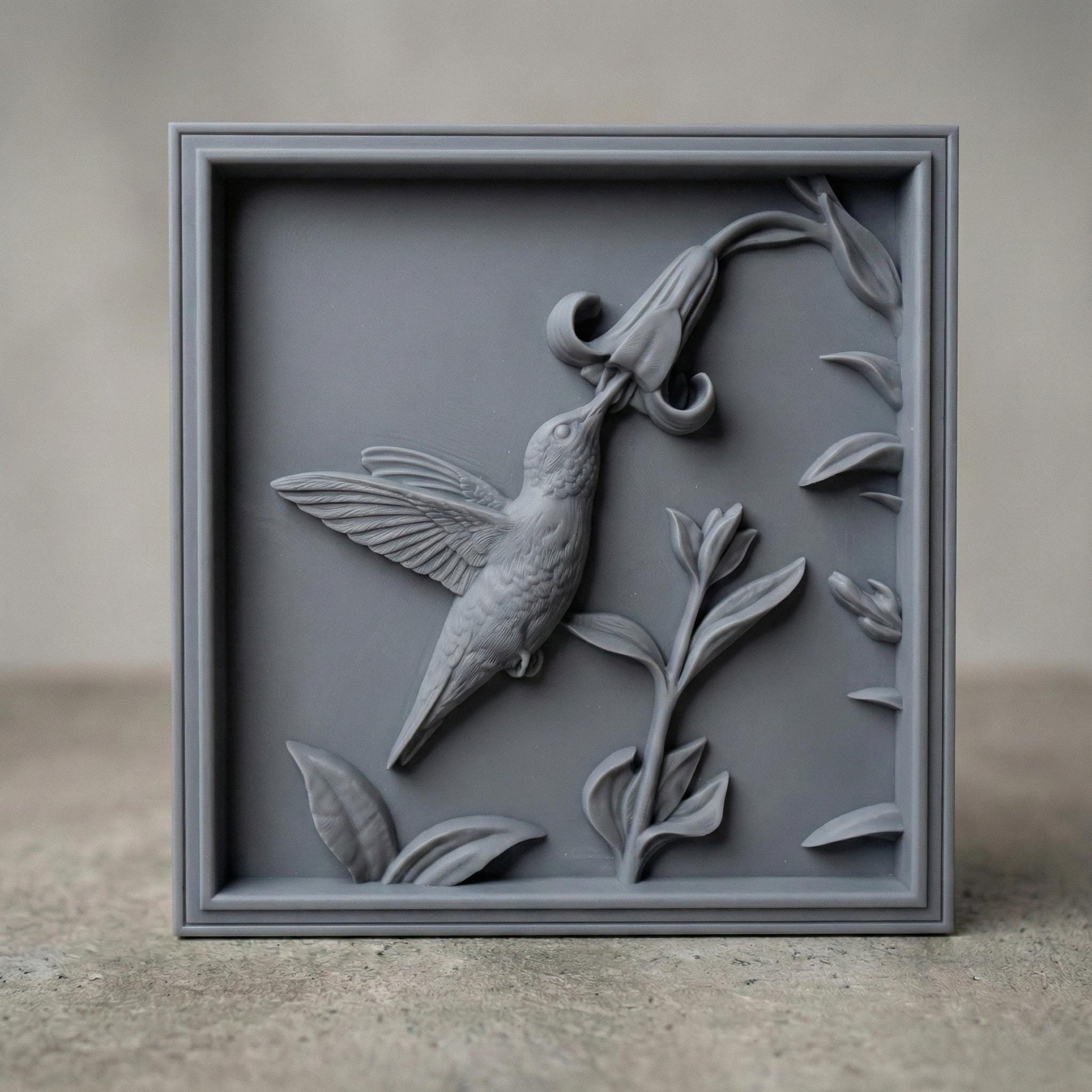 Elegant hummingbird bas relief STL depicting a hummingbird in flight feeding from cascading bell-shaped flowers, carved within a refined rectangular frame. The design features flowing leaves, delicate floral textures, and detailed feathers set against a smooth wood-grain background. Ideal for CNC wood carving, 3D printing, or framed wall art panels inspired by botanical and wildlife themes.