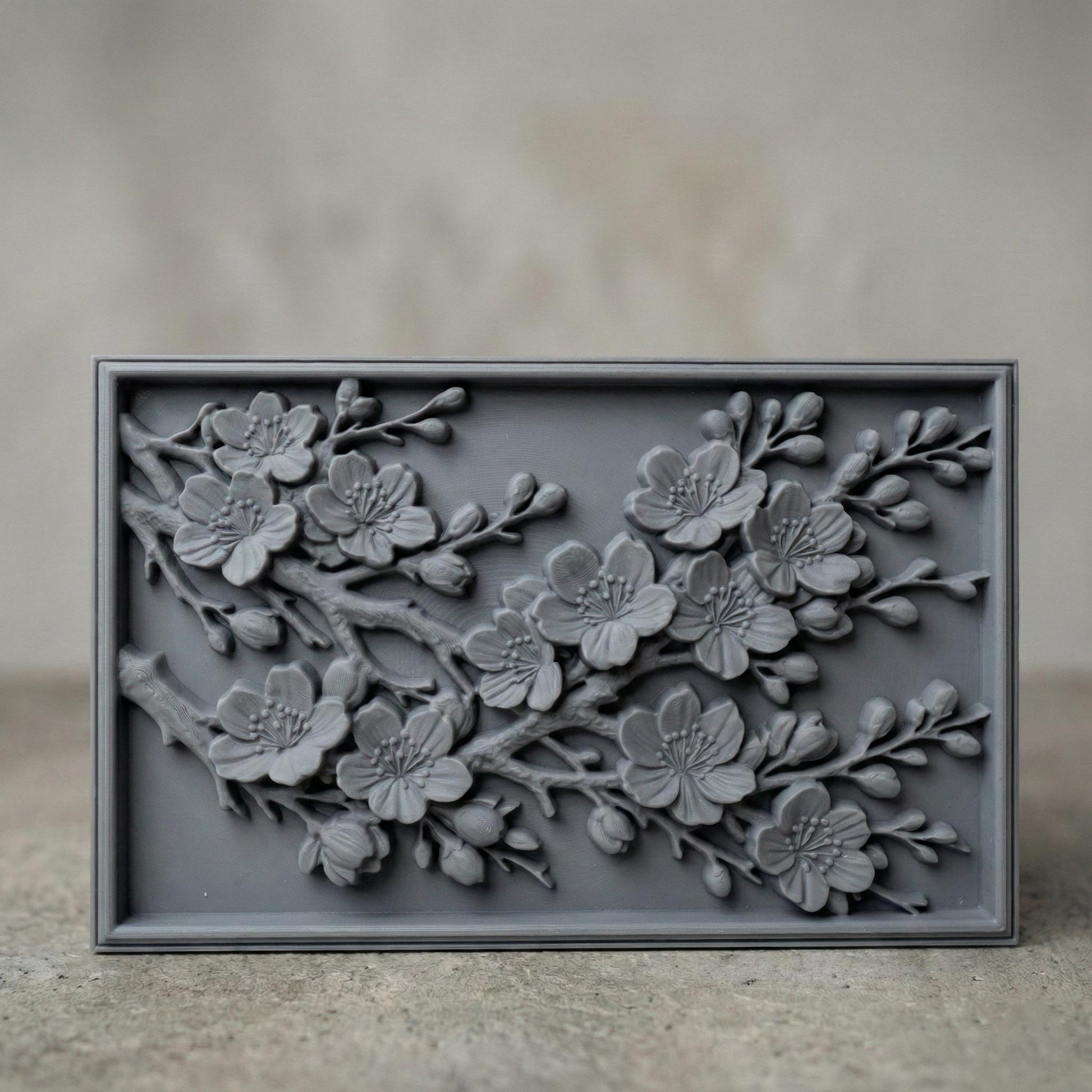 Rectangular bas-relief panel featuring detailed cherry blossom branches in full bloom. Delicate five-petal flowers with textured stamens and closed buds extend diagonally across the composition. Layered petals and organic wood grain texture enhance depth and realism. Framed in a clean border, this floral design symbolizes renewal, spring, and elegance, ideal for CNC carving, 3D printing, and decorative wall panels.