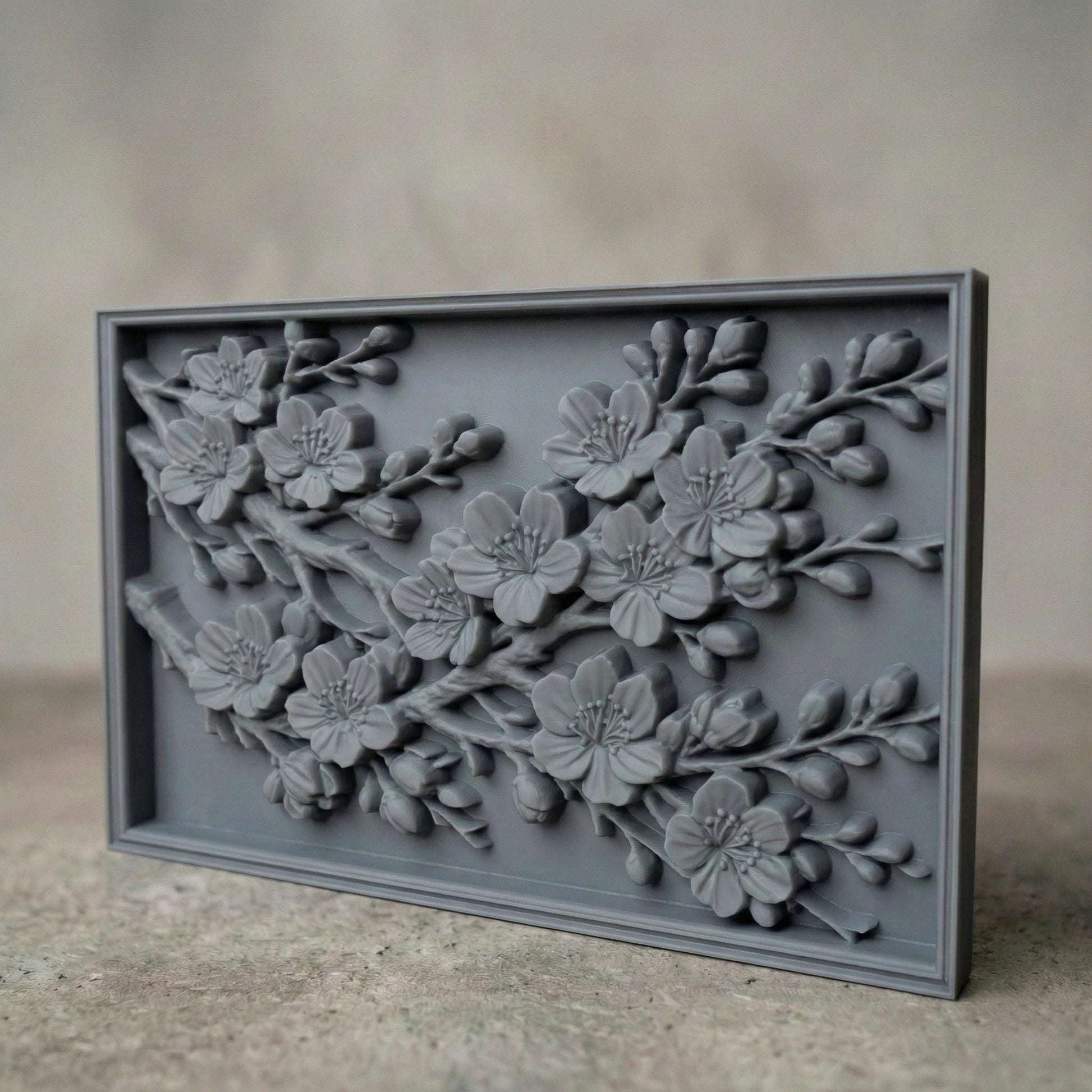 Rectangular bas-relief panel featuring detailed cherry blossom branches in full bloom. Delicate five-petal flowers with textured stamens and closed buds extend diagonally across the composition. Layered petals and organic wood grain texture enhance depth and realism. Framed in a clean border, this floral design symbolizes renewal, spring, and elegance, ideal for CNC carving, 3D printing, and decorative wall panels.