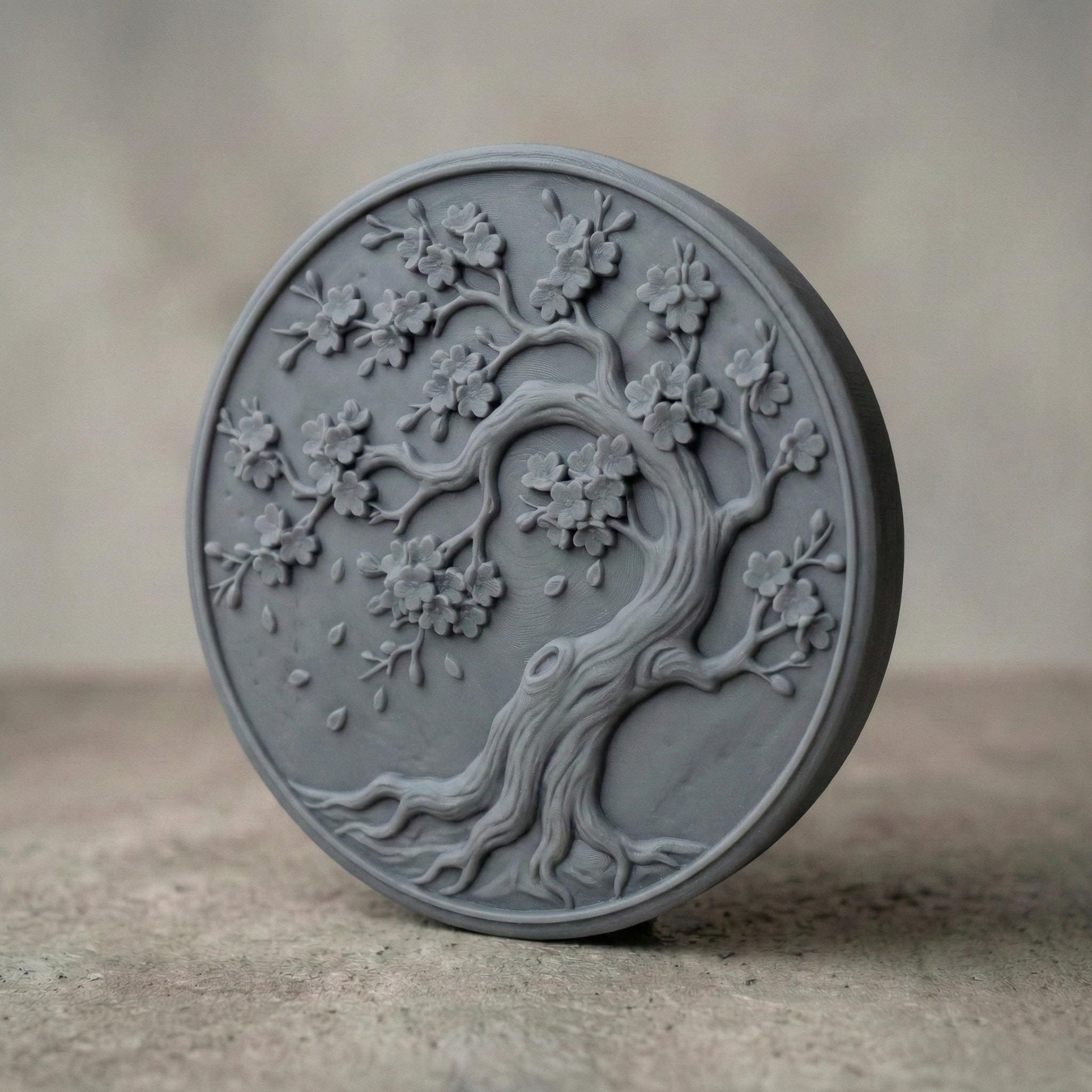 Round bas-relief panel featuring an elegant cherry blossom tree with flowing curved trunk, detailed branches, and blooming flowers. Delicate petals appear gently falling around the tree, creating a peaceful and natural composition. The circular frame enhances balance and harmony, making it ideal as decorative wall art for CNC carving or 3D printing with rich organic texture and depth.