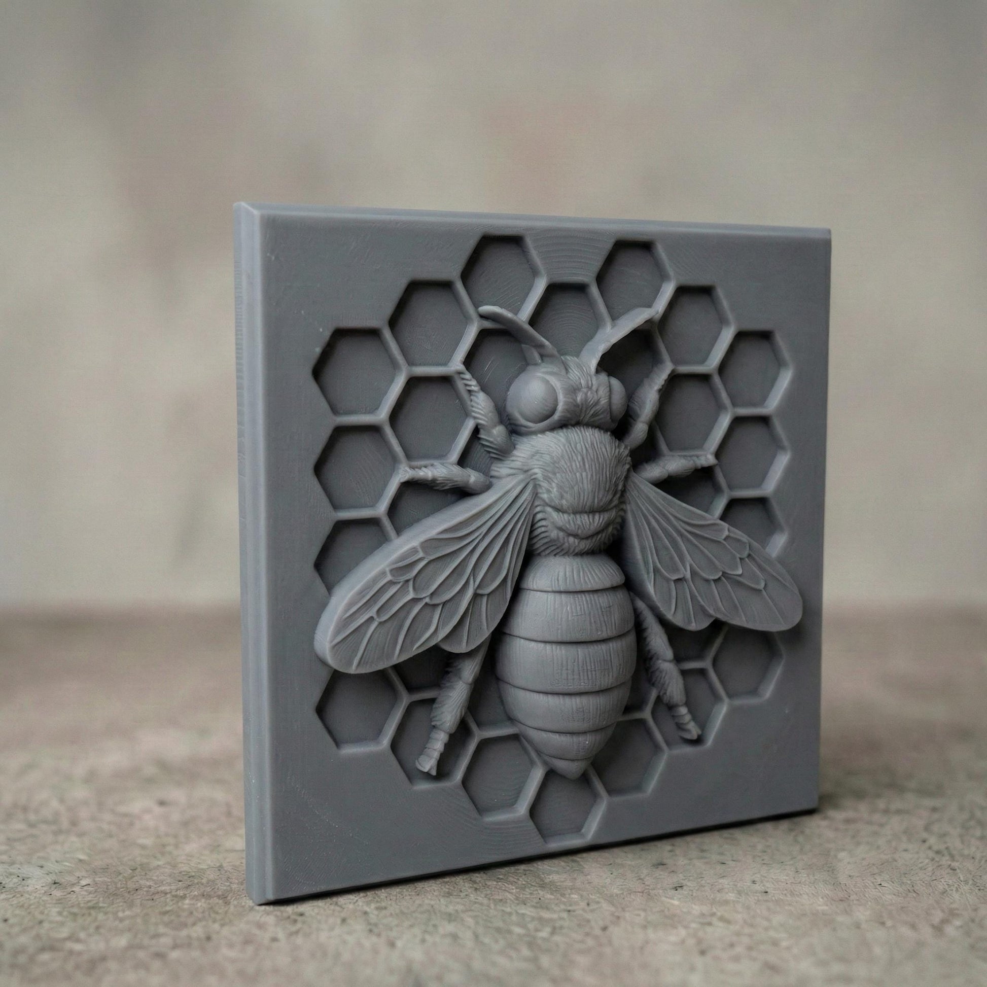 Detailed bas-relief sculpture of a honey bee centered on a hexagonal honeycomb background. The square panel features realistic wings, textured body, antennae, and symmetrical honeycomb cells carved behind the bee. Designed as decorative wall art with clean geometric framing, ideal for CNC carving or 3D printing projects with sharp detail and natural texture.