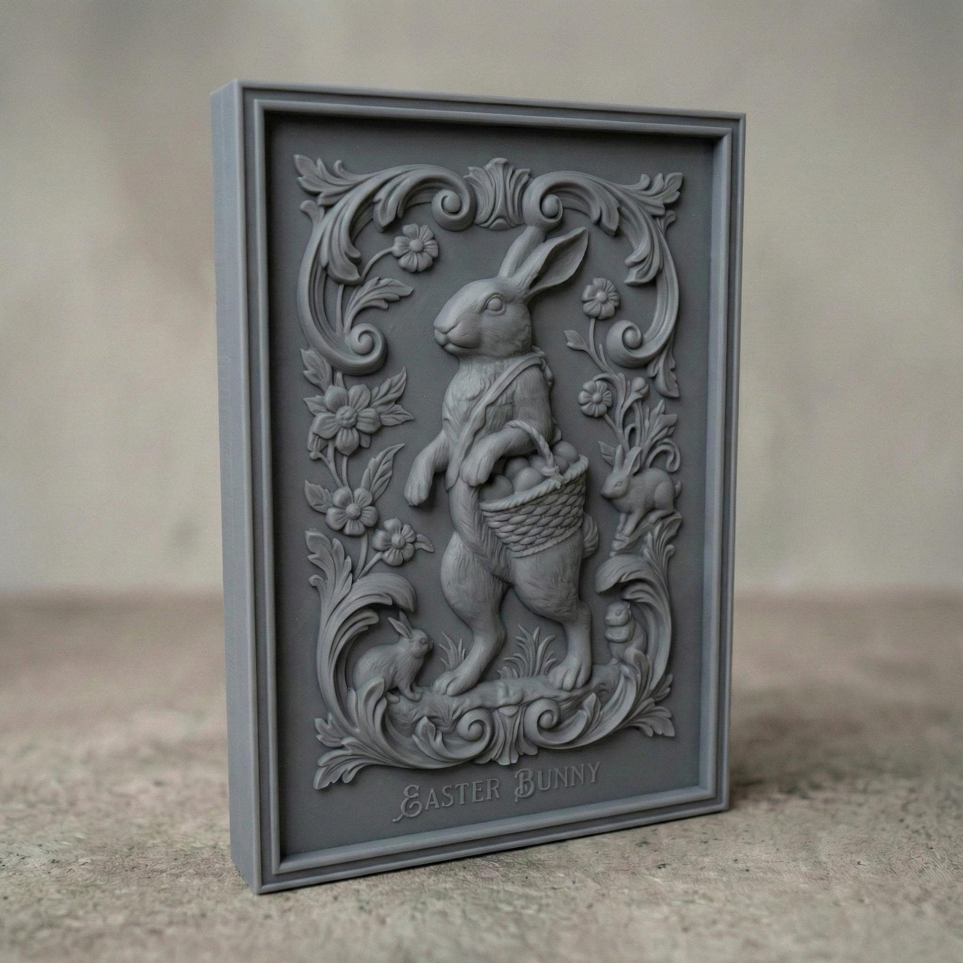 Decorative bas-relief panel featuring a standing Easter bunny holding a woven basket filled with eggs. The rabbit is surrounded by elegant floral scrollwork, blooming flowers, and small rabbits at the base. The framed vertical composition has a vintage ornamental style, designed for CNC carving or 3D printing as festive spring and Easter wall decor.