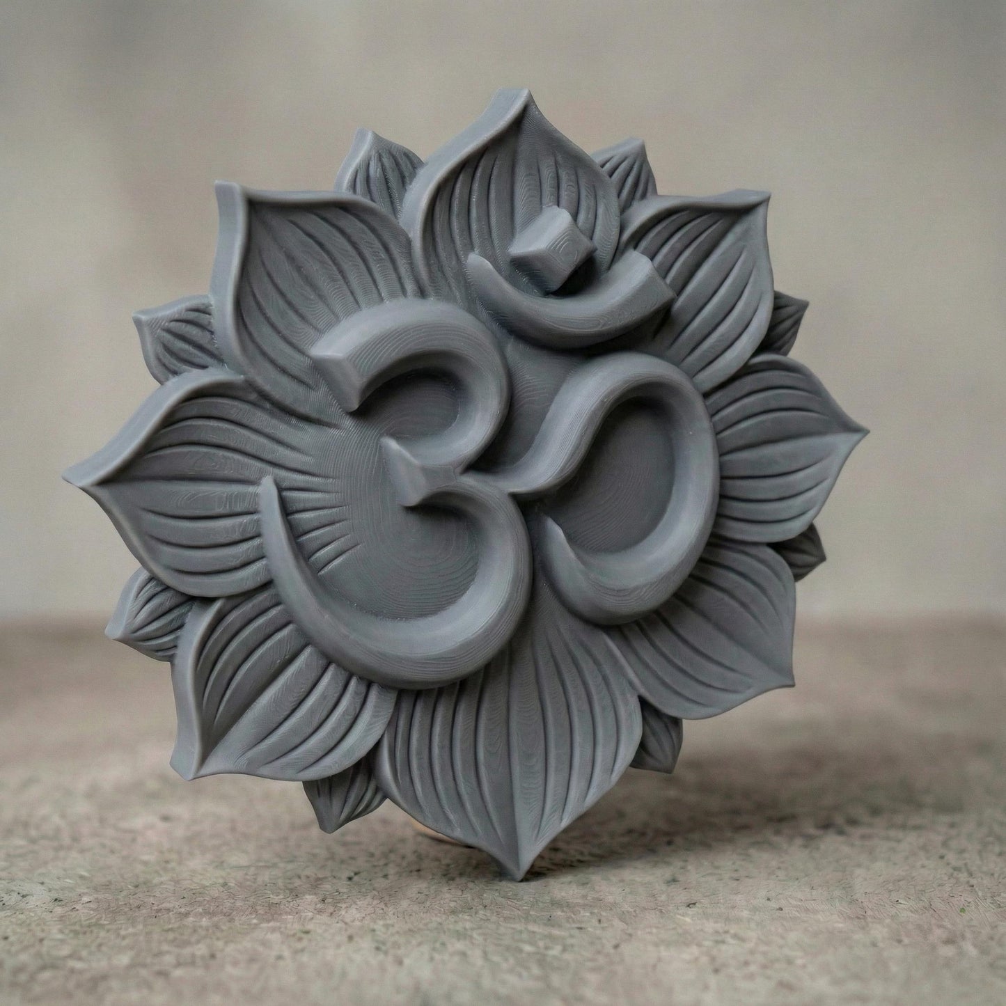 High-relief 3D Om symbol centered within a layered lotus flower mandala, featuring deep carved petals radiating outward in symmetrical harmony. The design shows smooth, flowing curves of the sacred Om sign raised above textured lotus leaves, ideal for CNC carving, bas-relief wall panels, spiritual décor, yoga studio art, and meditation room focal pieces. Intricate petal detailing enhances depth, shadow, and dimensional elegance.