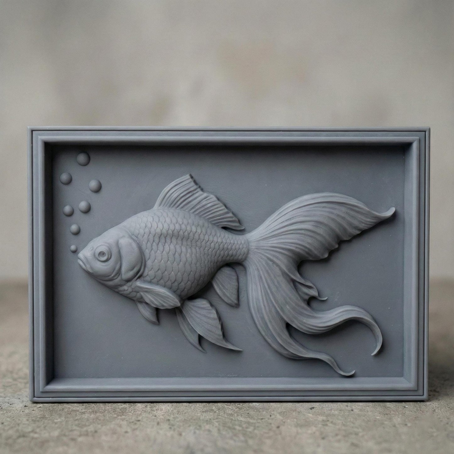 Elegant bas-relief carving of a flowing goldfish with detailed scales, large expressive eye, and long, graceful fins drifting through water bubbles. The design is shown as a framed wooden wall panel, a carved wood plaque on a workbench with chisels, and a standalone 3D sculpted fish model. The composition highlights fluid movement, layered depth, and ornamental aquatic beauty ideal for serene home décor.
