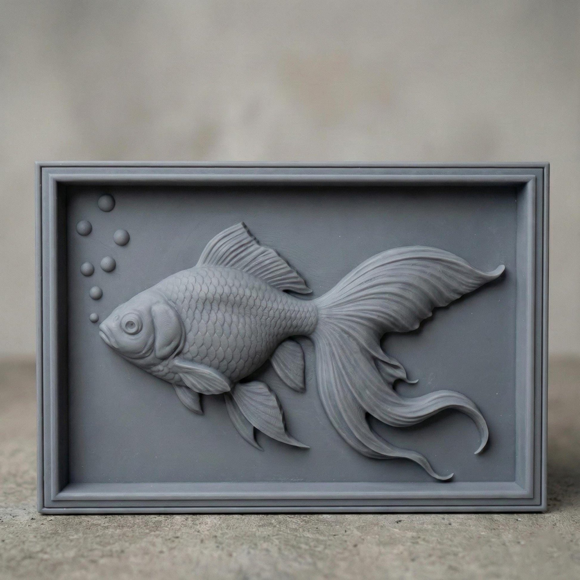 Elegant bas-relief carving of a flowing goldfish with detailed scales, large expressive eye, and long, graceful fins drifting through water bubbles. The design is shown as a framed wooden wall panel, a carved wood plaque on a workbench with chisels, and a standalone 3D sculpted fish model. The composition highlights fluid movement, layered depth, and ornamental aquatic beauty ideal for serene home décor.