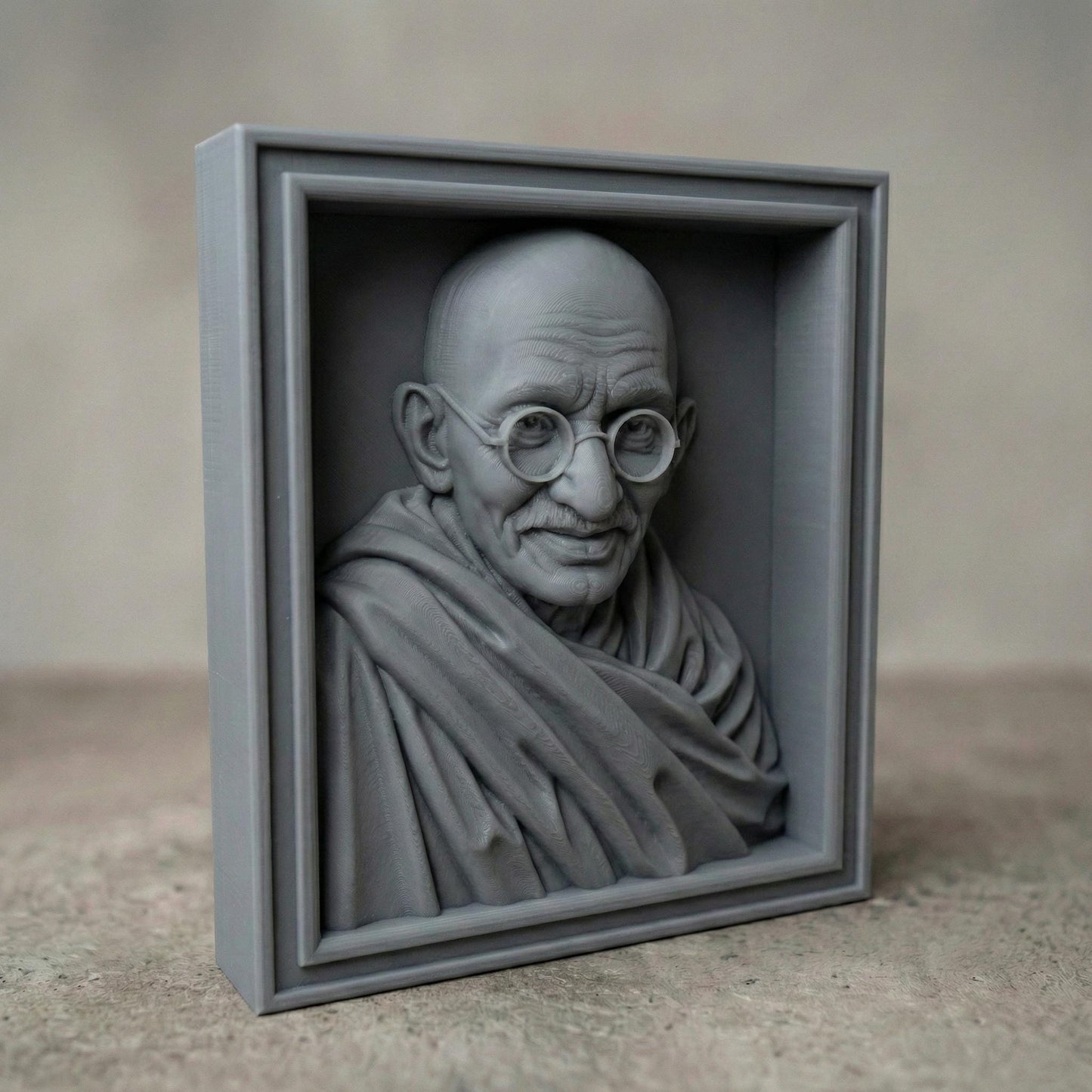 Highly detailed wooden bas-relief sculpture of Mahatma Gandhi featuring his serene expression, round glasses, bald head, and draped shawl. The portrait is carved in rich wood grain texture, highlighting facial wrinkles and soft folds of fabric. Displayed as both a freestanding bust and framed wall relief, symbolizing peace, wisdom, humility, and spiritual leadership.