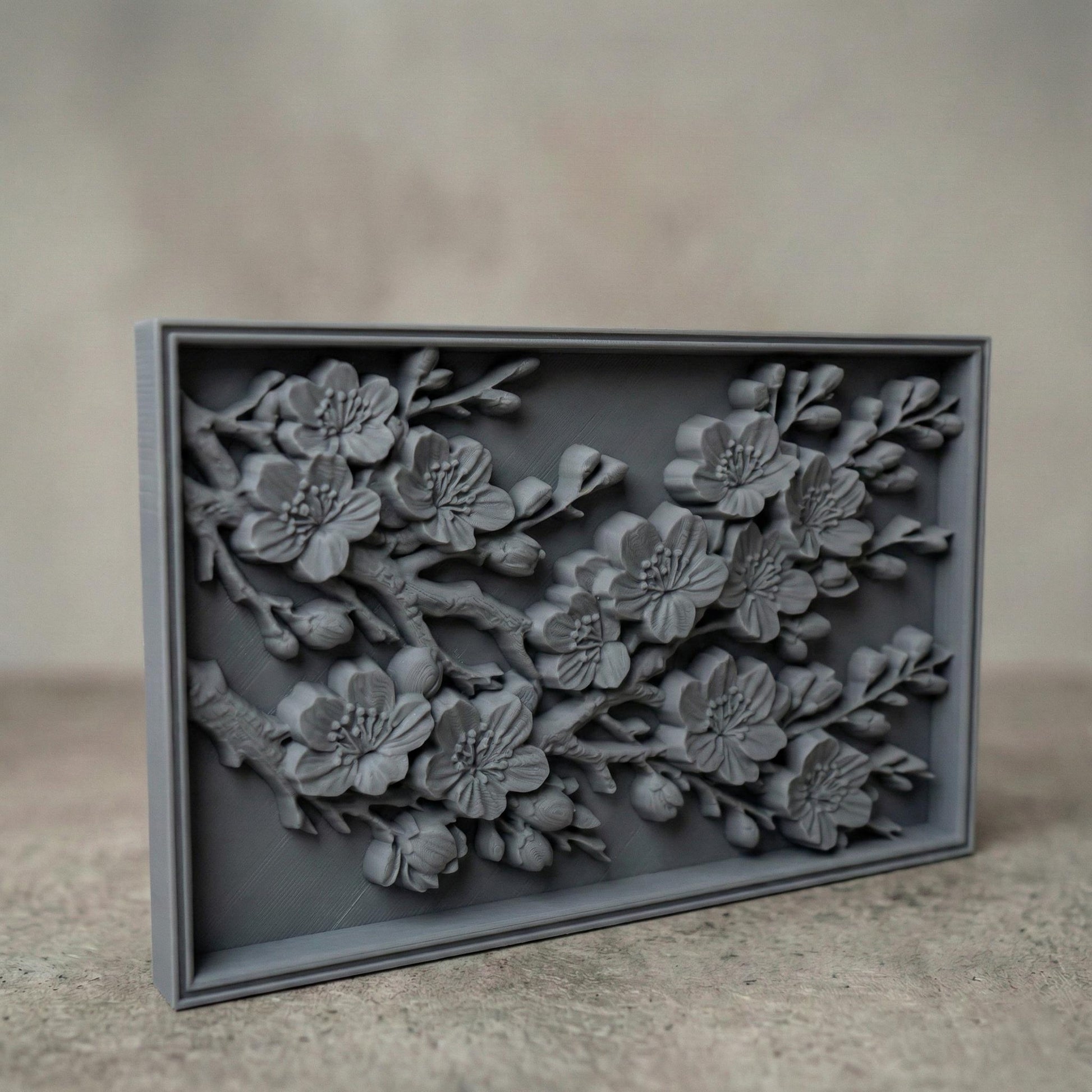 Rectangular bas-relief panel featuring detailed cherry blossom branches in full bloom. Delicate five-petal flowers with textured stamens and closed buds extend diagonally across the composition. Layered petals and organic wood grain texture enhance depth and realism. Framed in a clean border, this floral design symbolizes renewal, spring, and elegance, ideal for CNC carving, 3D printing, and decorative wall panels.