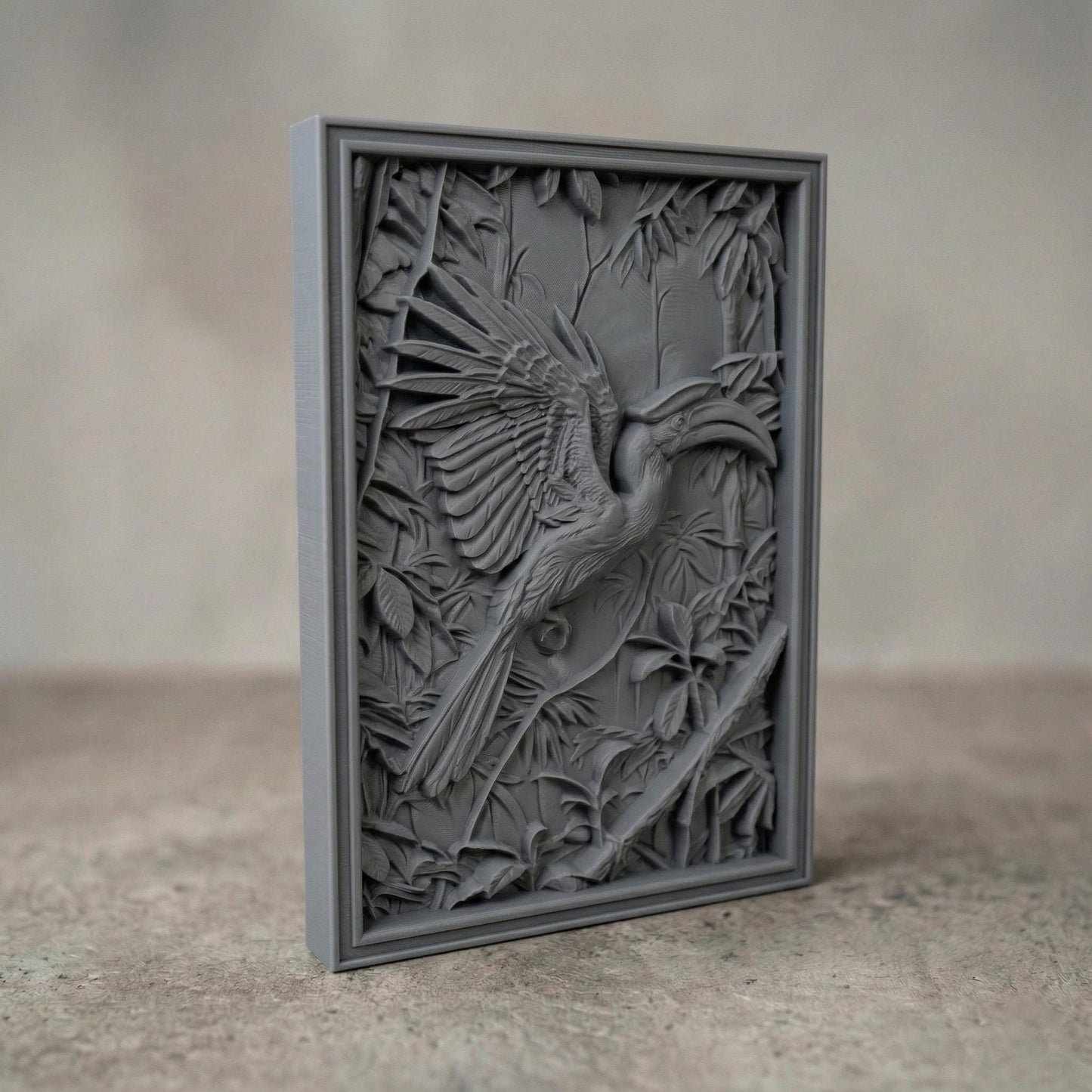 Highly detailed bas-relief carving of a hornbill bird with wide spread wings perched among dense tropical leaves and branches. The bird’s long curved beak and layered feathers are sculpted in deep relief, surrounded by jungle foliage that creates a rich wildlife scene suitable for CNC carving, 3D printing, or decorative wall art.