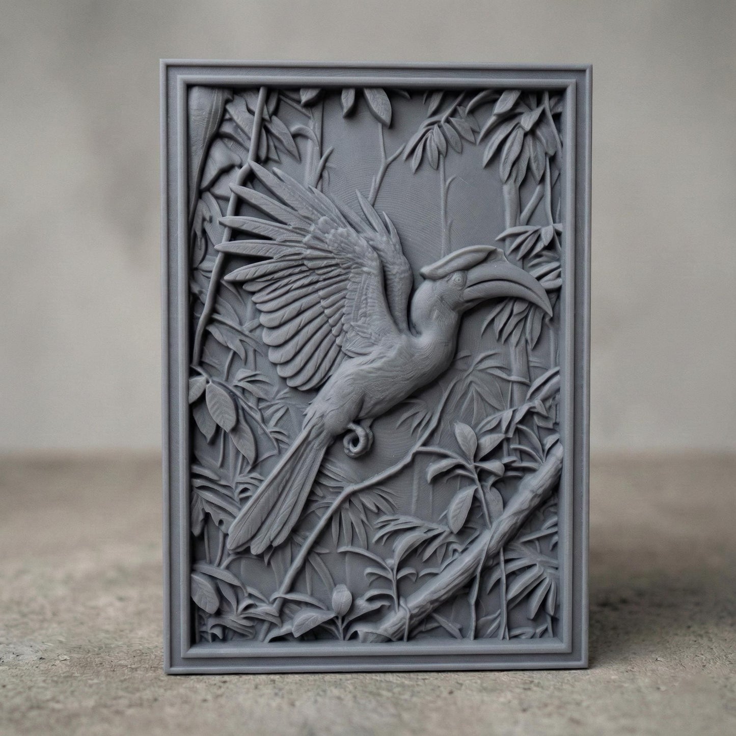 Highly detailed bas-relief carving of a hornbill bird with wide spread wings perched among dense tropical leaves and branches. The bird’s long curved beak and layered feathers are sculpted in deep relief, surrounded by jungle foliage that creates a rich wildlife scene suitable for CNC carving, 3D printing, or decorative wall art.