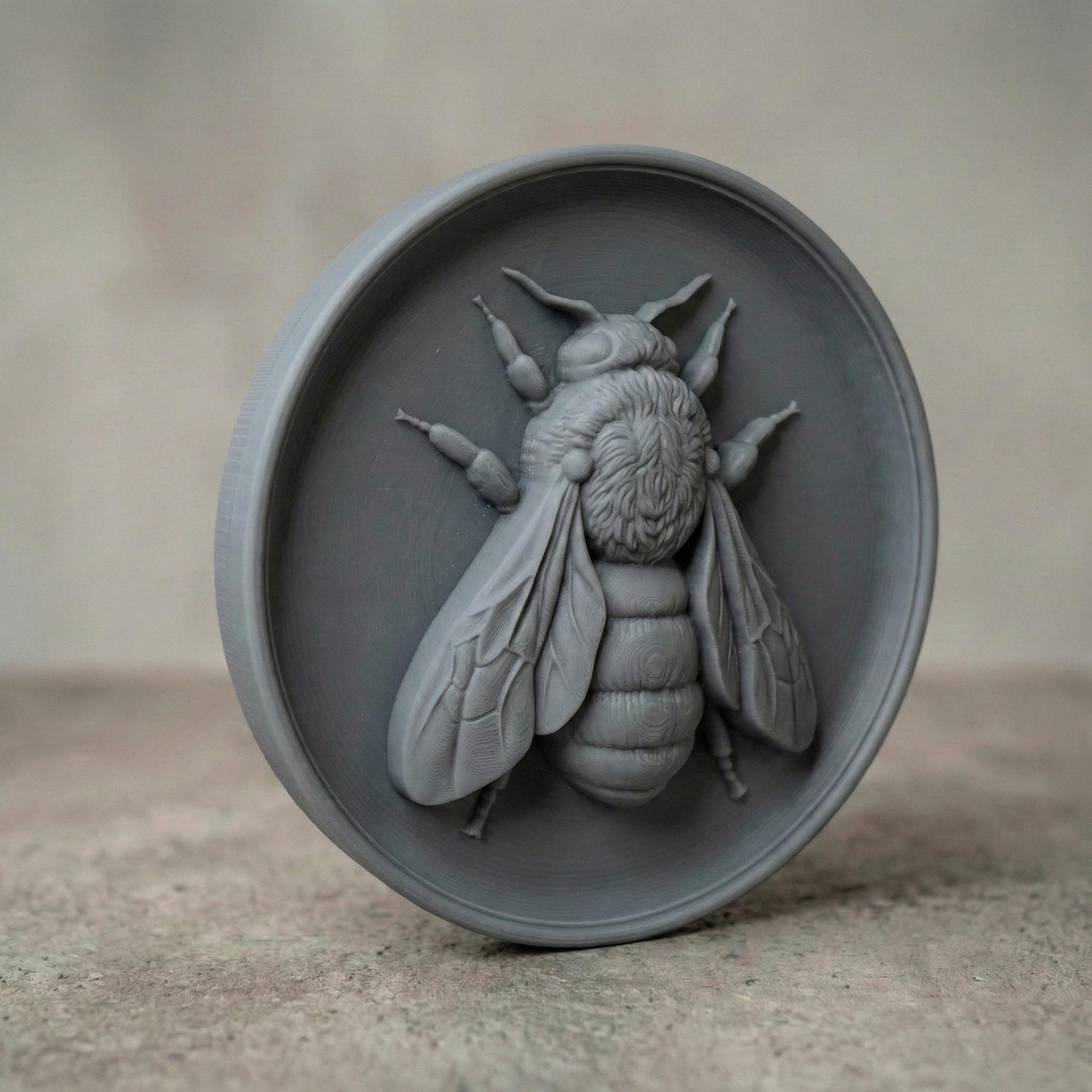 Round bas-relief featuring a realistic honey bee with detailed wings, textured thorax, and segmented abdomen carved in deep relief. The bee is centered on a circular wood panel with natural grain patterns, symbolizing spring renewal, pollination, and growth. Strong shadow lines and layered carving add depth and dimension, making this design ideal for CNC carving, 3D printing, and spring farmhouse wall decor.