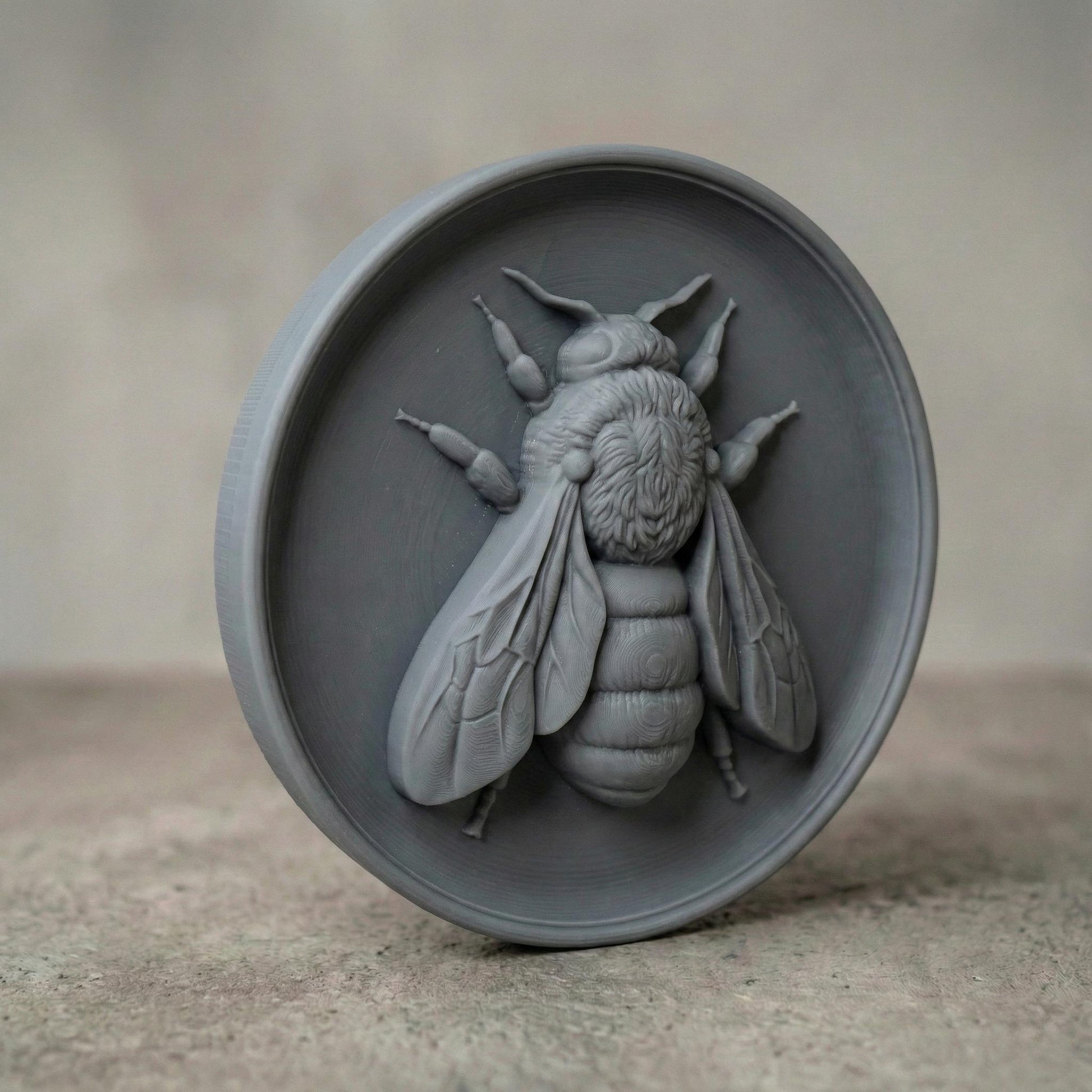 Round bas-relief featuring a realistic honey bee with detailed wings, textured thorax, and segmented abdomen carved in deep relief. The bee is centered on a circular wood panel with natural grain patterns, symbolizing spring renewal, pollination, and growth. Strong shadow lines and layered carving add depth and dimension, making this design ideal for CNC carving, 3D printing, and spring farmhouse wall decor.