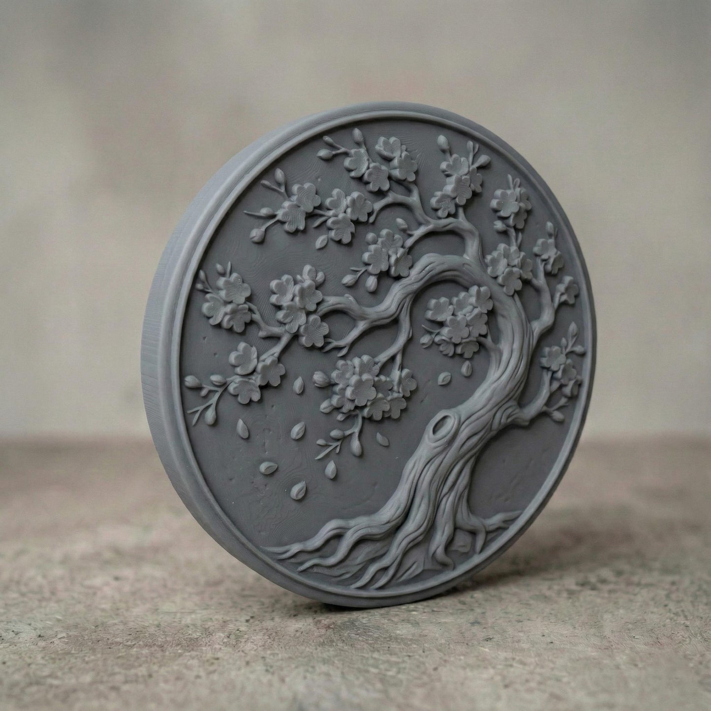 Round bas-relief panel featuring an elegant cherry blossom tree with flowing curved trunk, detailed branches, and blooming flowers. Delicate petals appear gently falling around the tree, creating a peaceful and natural composition. The circular frame enhances balance and harmony, making it ideal as decorative wall art for CNC carving or 3D printing with rich organic texture and depth.