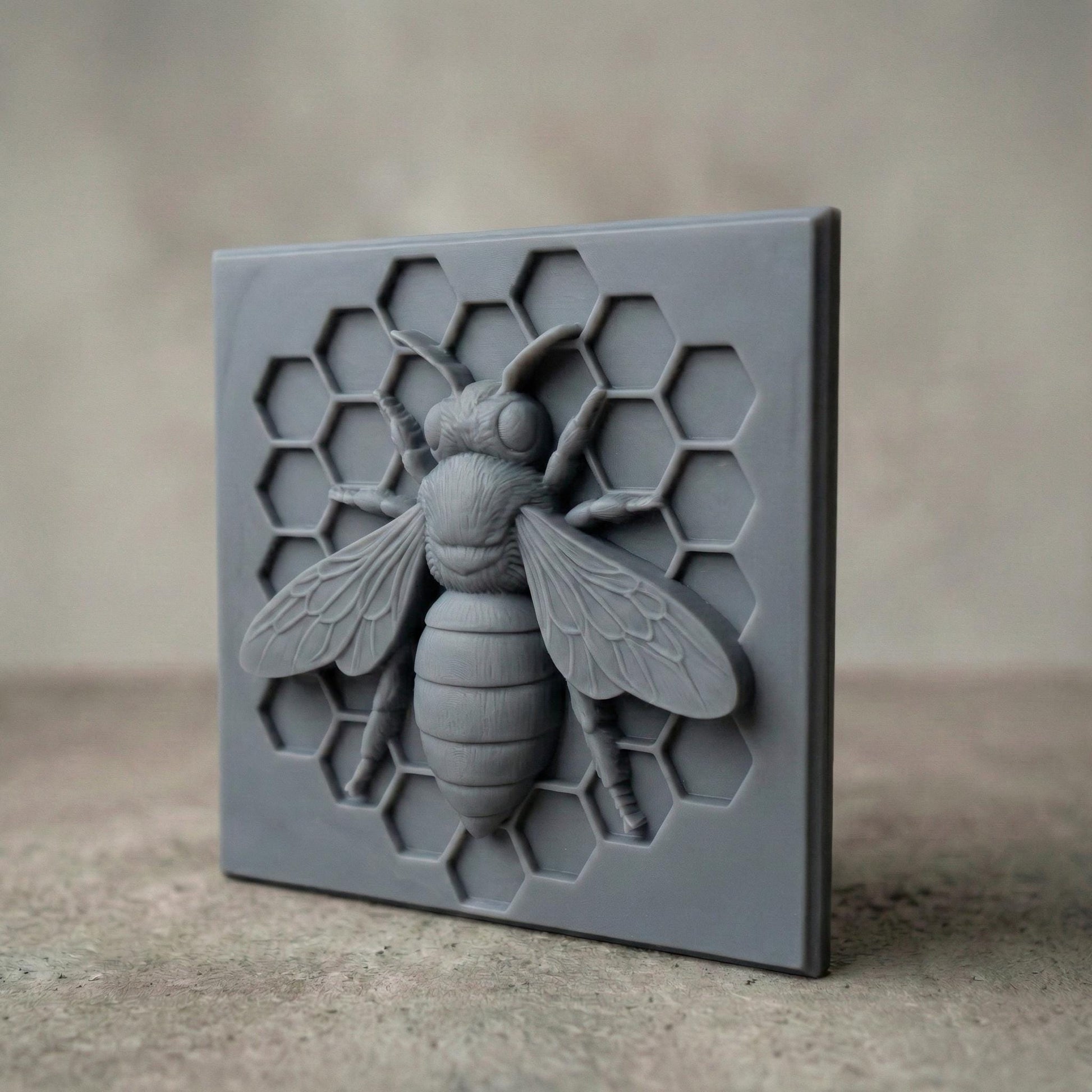 Detailed bas-relief sculpture of a honey bee centered on a hexagonal honeycomb background. The square panel features realistic wings, textured body, antennae, and symmetrical honeycomb cells carved behind the bee. Designed as decorative wall art with clean geometric framing, ideal for CNC carving or 3D printing projects with sharp detail and natural texture.