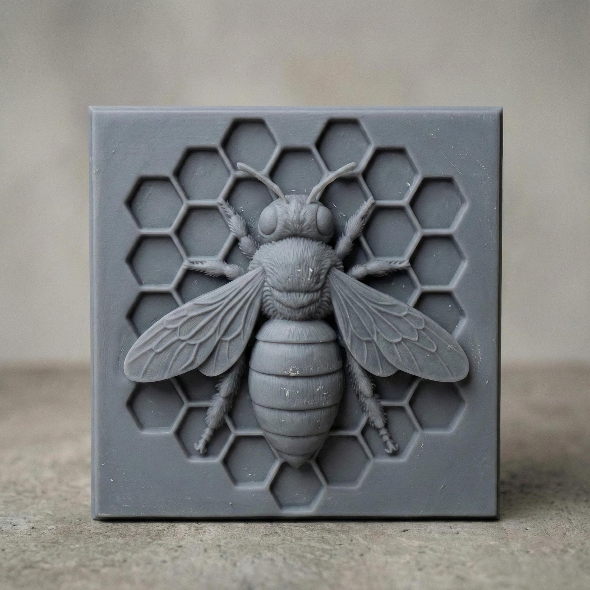 Detailed bas-relief sculpture of a honey bee centered on a hexagonal honeycomb background. The square panel features realistic wings, textured body, antennae, and symmetrical honeycomb cells carved behind the bee. Designed as decorative wall art with clean geometric framing, ideal for CNC carving or 3D printing projects with sharp detail and natural texture.
