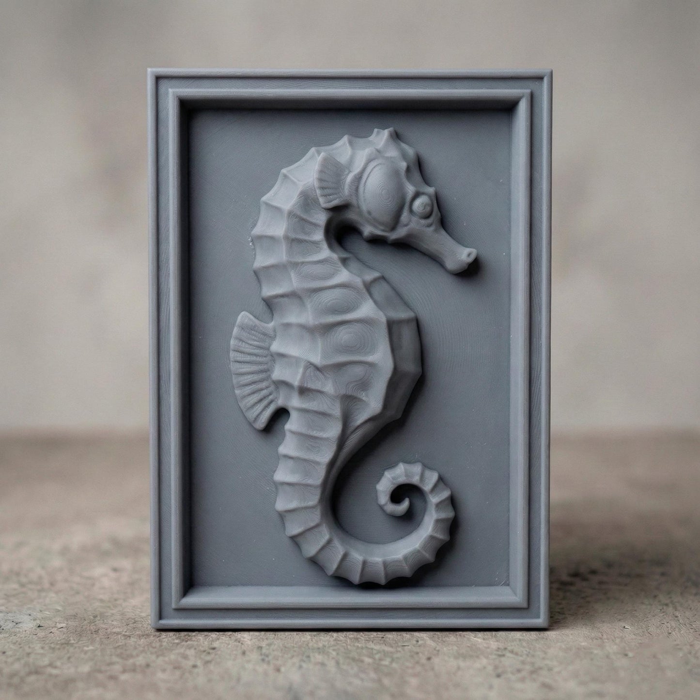 Detailed bas-relief seahorse carving mounted inside a rectangular wooden frame, featuring layered scales, curved tail, and textured dorsal ridges. The marine creature is sculpted in a relief style suitable for CNC carving or 3D printing, creating elegant coastal wall decor inspired by ocean life and nautical themes.