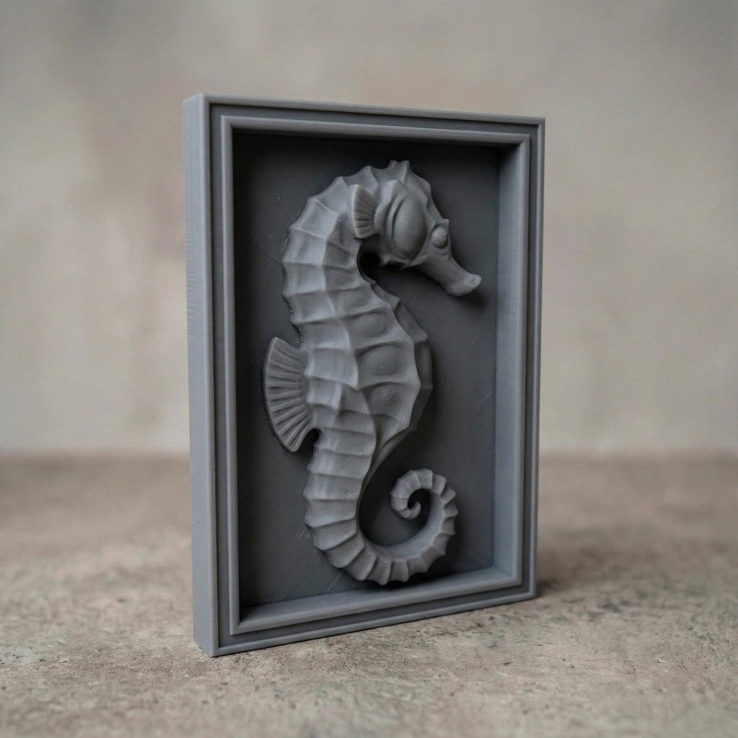 Detailed bas-relief seahorse carving mounted inside a rectangular wooden frame, featuring layered scales, curved tail, and textured dorsal ridges. The marine creature is sculpted in a relief style suitable for CNC carving or 3D printing, creating elegant coastal wall decor inspired by ocean life and nautical themes.