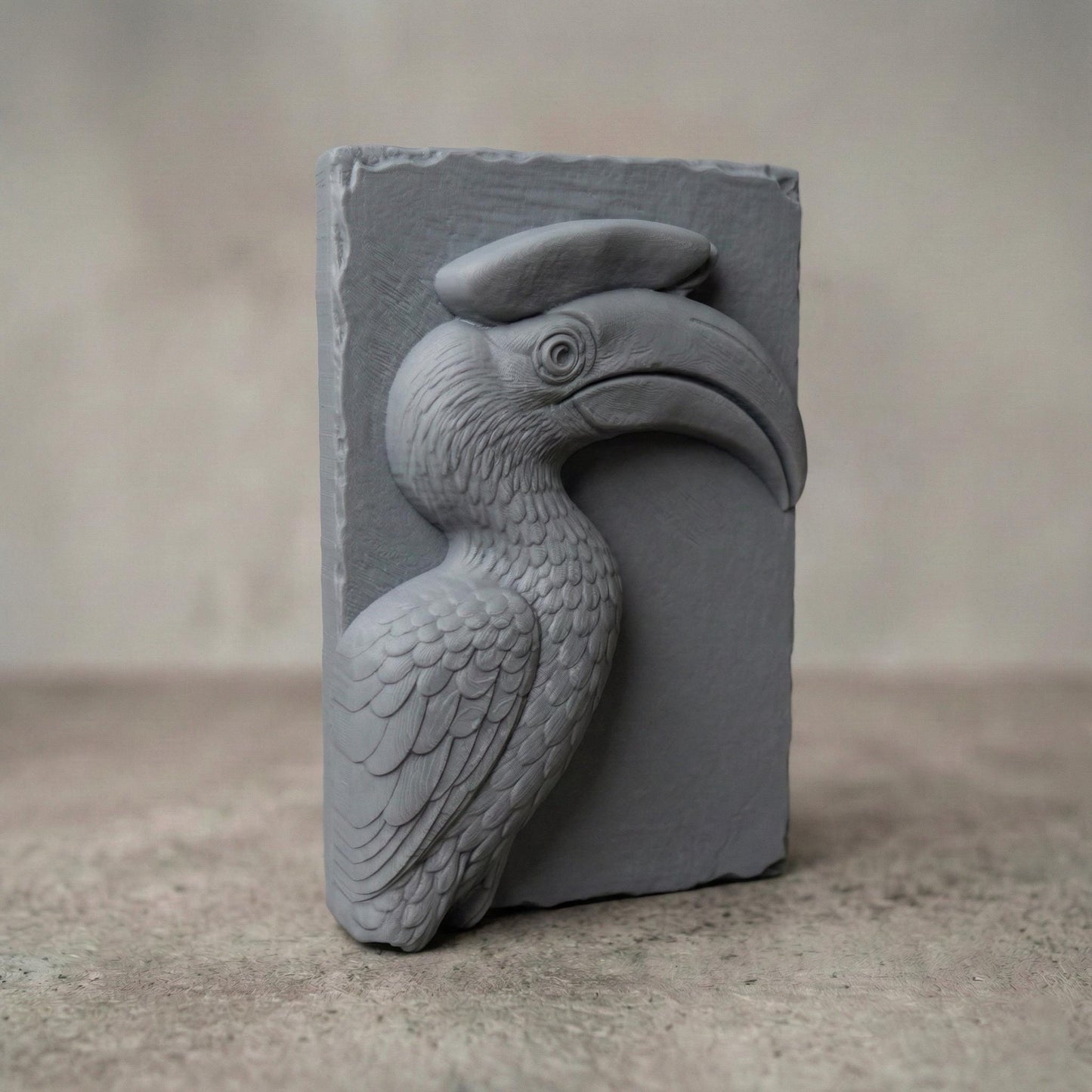 Detailed bas-relief carving of a hornbill bird head with a large curved beak and distinctive casque, sculpted with layered feathers and smooth contours. The tropical wildlife design is carved on a natural wood slab style background with organic edges, creating elegant jungle-inspired spring and summer wall art suitable for CNC carving or 3D printing.