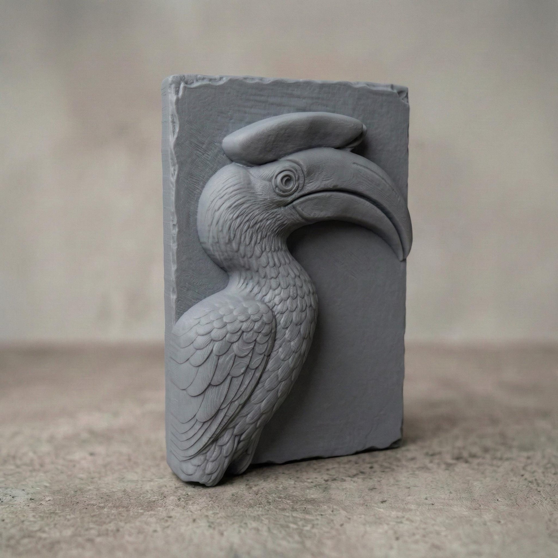 Detailed bas-relief carving of a hornbill bird head with a large curved beak and distinctive casque, sculpted with layered feathers and smooth contours. The tropical wildlife design is carved on a natural wood slab style background with organic edges, creating elegant jungle-inspired spring and summer wall art suitable for CNC carving or 3D printing.