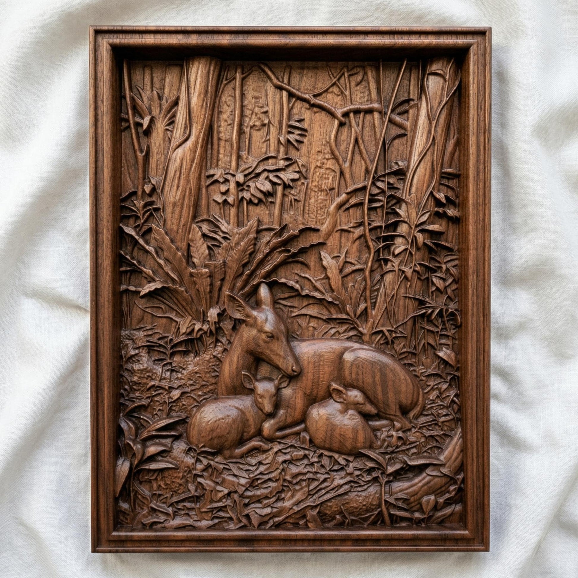 Detailed bas-relief carving of a deer resting peacefully with two fawns nestled beside it in a dense forest setting, surrounded by lush foliage, textured leaves, and tall trees, capturing warmth, protection, and tranquility in a natural woodland scene.