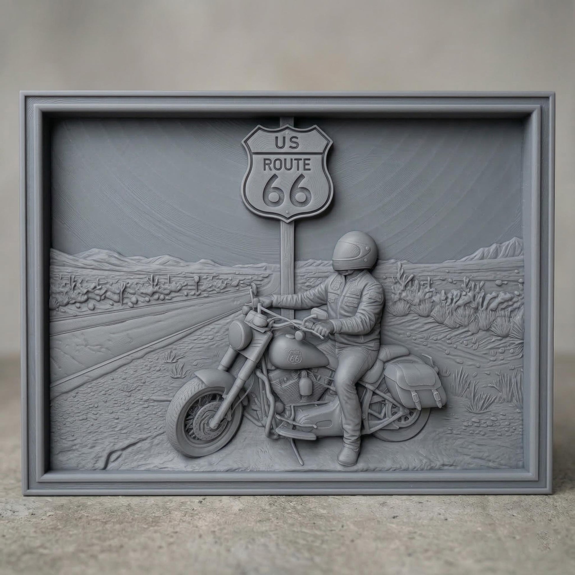Detailed bas-relief scene of a motorcycle rider parked beside a US Route 66 road sign in a desert highway landscape. The rider wears a helmet and leather riding gear while sitting on a classic touring motorcycle with saddlebags. The background shows an open road stretching through desert terrain with cacti and distant mountains, symbolizing freedom, adventure, and the iconic American road trip culture.