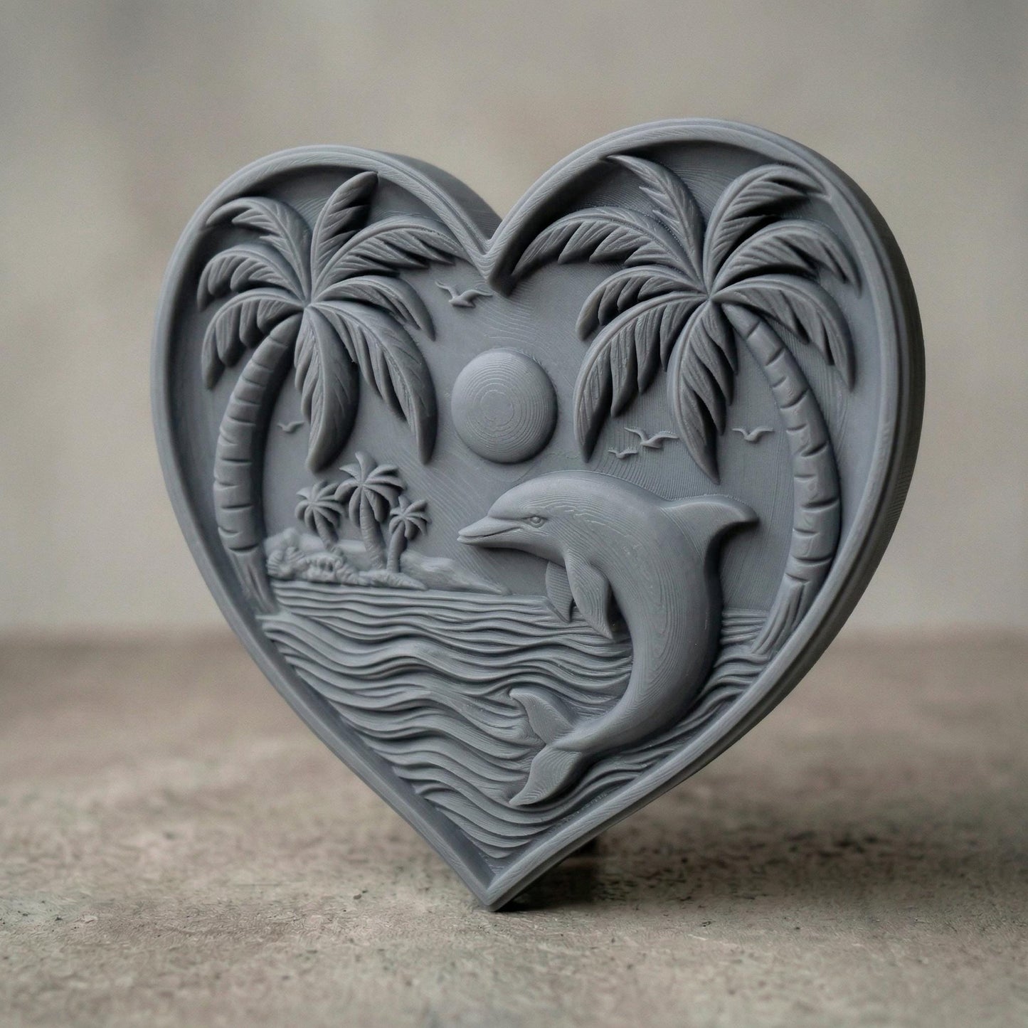 Heart-shaped bas-relief carving featuring a leaping dolphin in ocean waves beneath a tropical sunset, framed by curved palm trees and a small island in the background. Fine wood grain texture enhances depth, with birds in the sky and layered water lines creating a serene coastal scene symbolizing love, freedom, and tranquility.