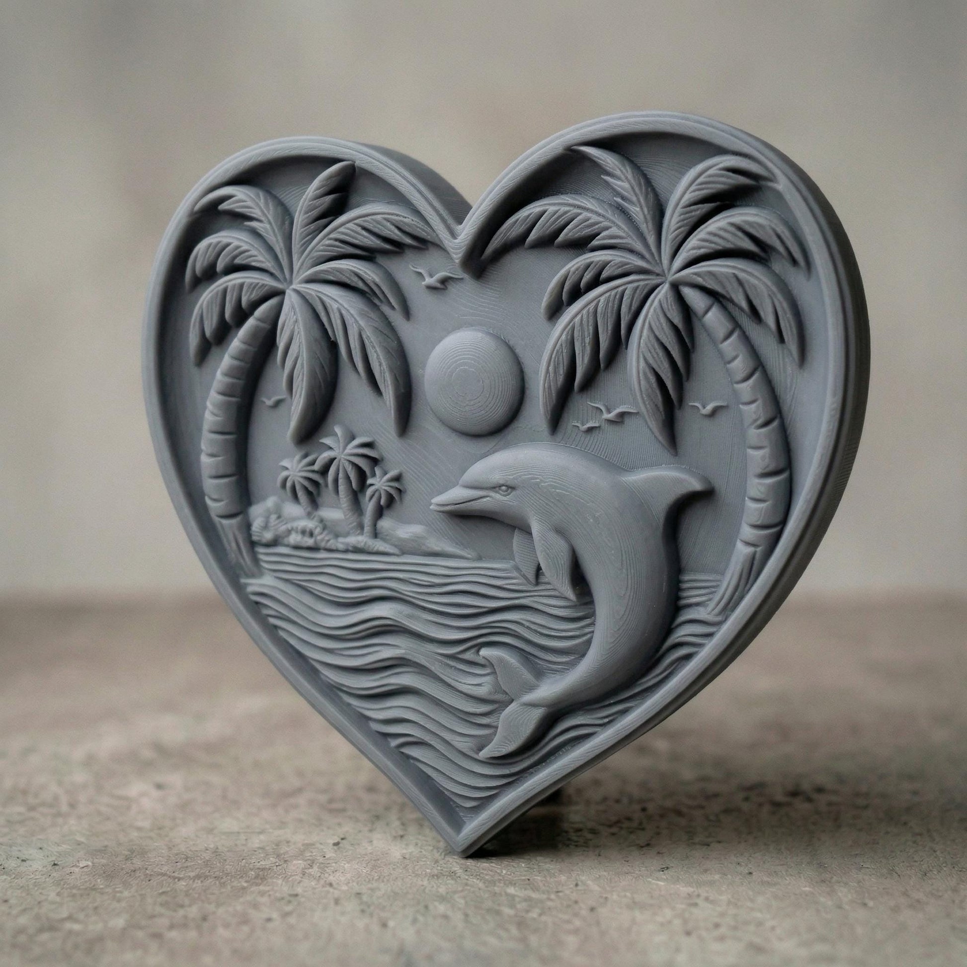 Heart-shaped bas-relief carving featuring a leaping dolphin in ocean waves beneath a tropical sunset, framed by curved palm trees and a small island in the background. Fine wood grain texture enhances depth, with birds in the sky and layered water lines creating a serene coastal scene symbolizing love, freedom, and tranquility.