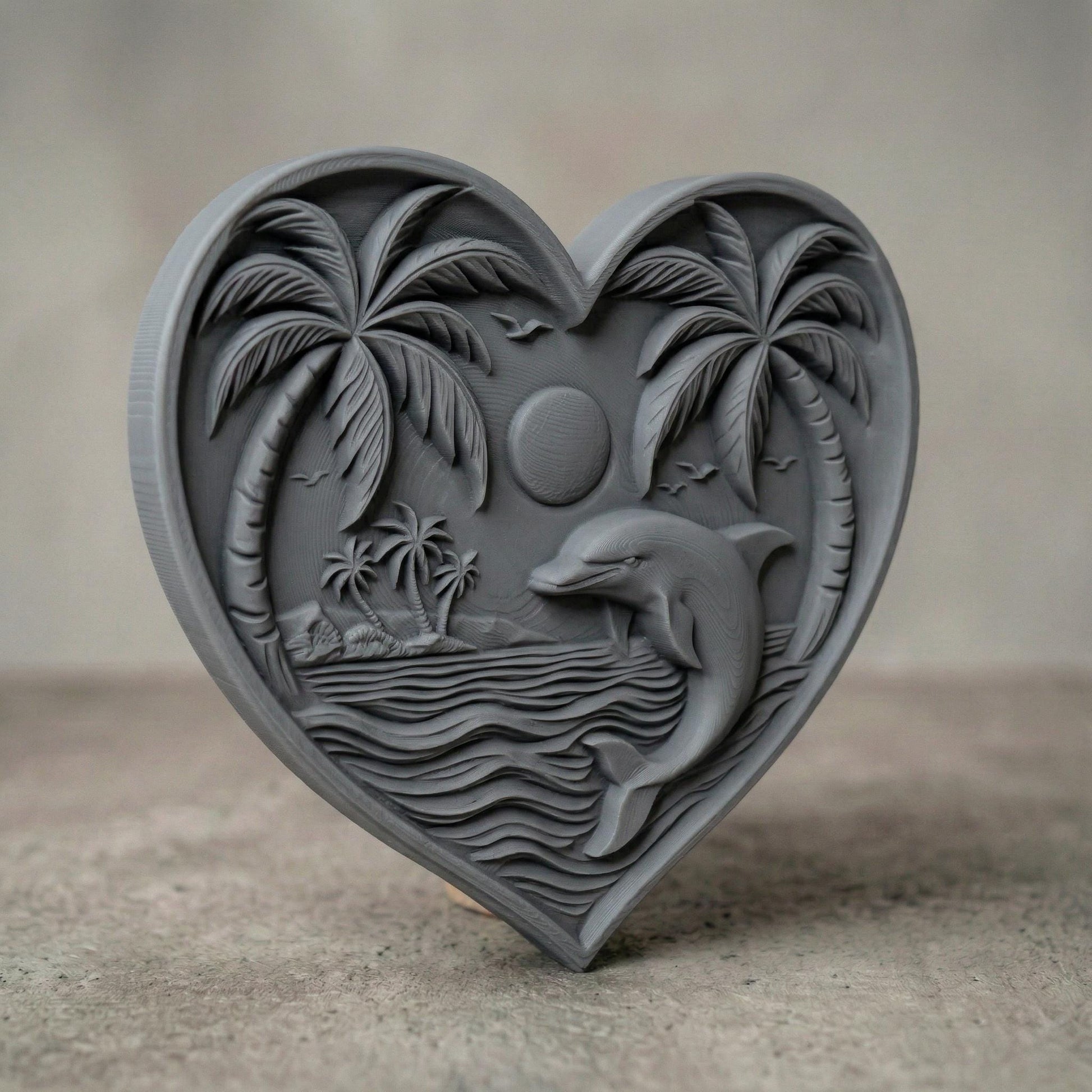 Heart-shaped bas-relief carving featuring a leaping dolphin in ocean waves beneath a tropical sunset, framed by curved palm trees and a small island in the background. Fine wood grain texture enhances depth, with birds in the sky and layered water lines creating a serene coastal scene symbolizing love, freedom, and tranquility.