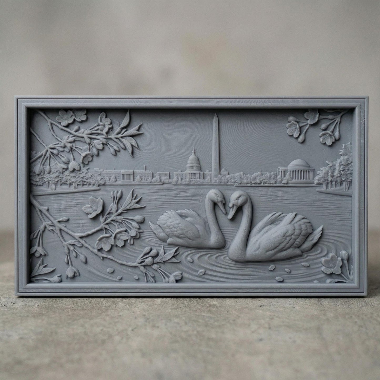 Detailed bas-relief carving of two swans forming a heart shape on rippling water, surrounded by blossoming branches. In the background, the Washington Monument and Capitol building rise along a serene lakeside skyline. Fine wood grain texture and layered depth create an elegant, romantic composition symbolizing love and unity in a peaceful natural setting.