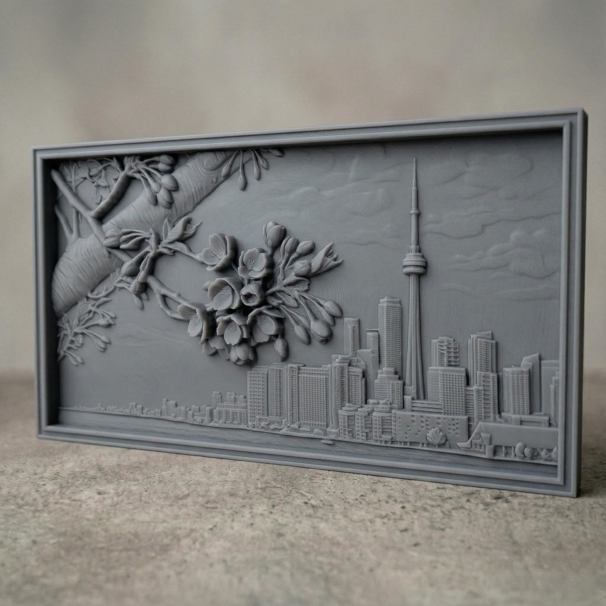 Elegant bas-relief carving of Toronto skyline featuring the CN Tower and Rogers Centre beneath a detailed cherry blossom branch in full spring bloom. The blossoms stretch across the scene above layered city buildings, with rich wood grain texture and smooth depth creating a harmonious blend of urban architecture and natural beauty.