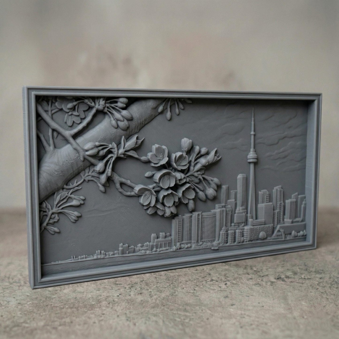 Elegant bas-relief carving of Toronto skyline featuring the CN Tower and Rogers Centre beneath a detailed cherry blossom branch in full spring bloom. The blossoms stretch across the scene above layered city buildings, with rich wood grain texture and smooth depth creating a harmonious blend of urban architecture and natural beauty.