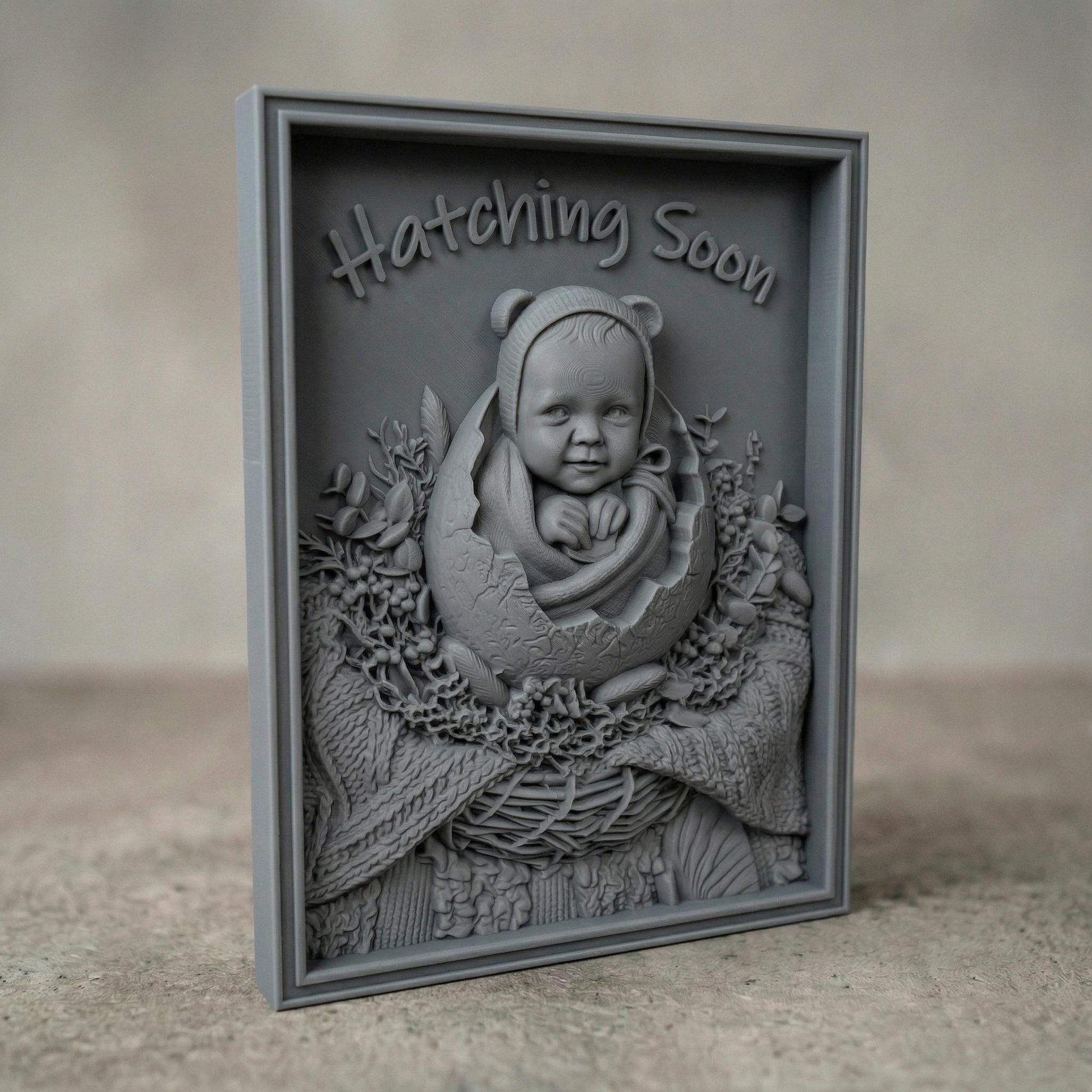 Highly detailed bas-relief carving of a smiling baby emerging from a cracked egg, surrounded by a woven nest and delicate foliage. The phrase “Hatching Soon” arches above, symbolizing anticipation and new life. Soft textures and layered wood grain create a warm, nurturing scene ideal for nursery decor or pregnancy announcements.