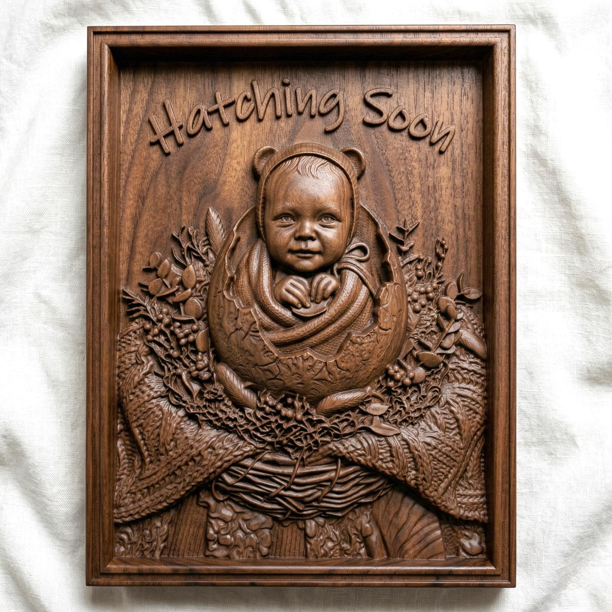 Highly detailed bas-relief carving of a smiling baby emerging from a cracked egg, surrounded by a woven nest and delicate foliage. The phrase “Hatching Soon” arches above, symbolizing anticipation and new life. Soft textures and layered wood grain create a warm, nurturing scene ideal for nursery decor or pregnancy announcements.