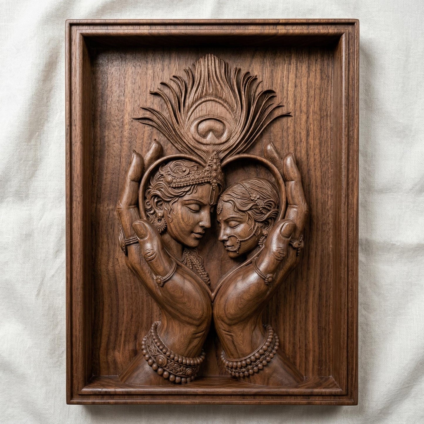 Intricately carved bas-relief of Radha and Krishna in an intimate embrace, framed by graceful hands forming a heart shape. A detailed peacock feather rises above, symbolizing divine love and harmony. Ornate jewelry, flowing hair, and smooth wood grain textures enhance the spiritual and romantic essence of this elegant composition.