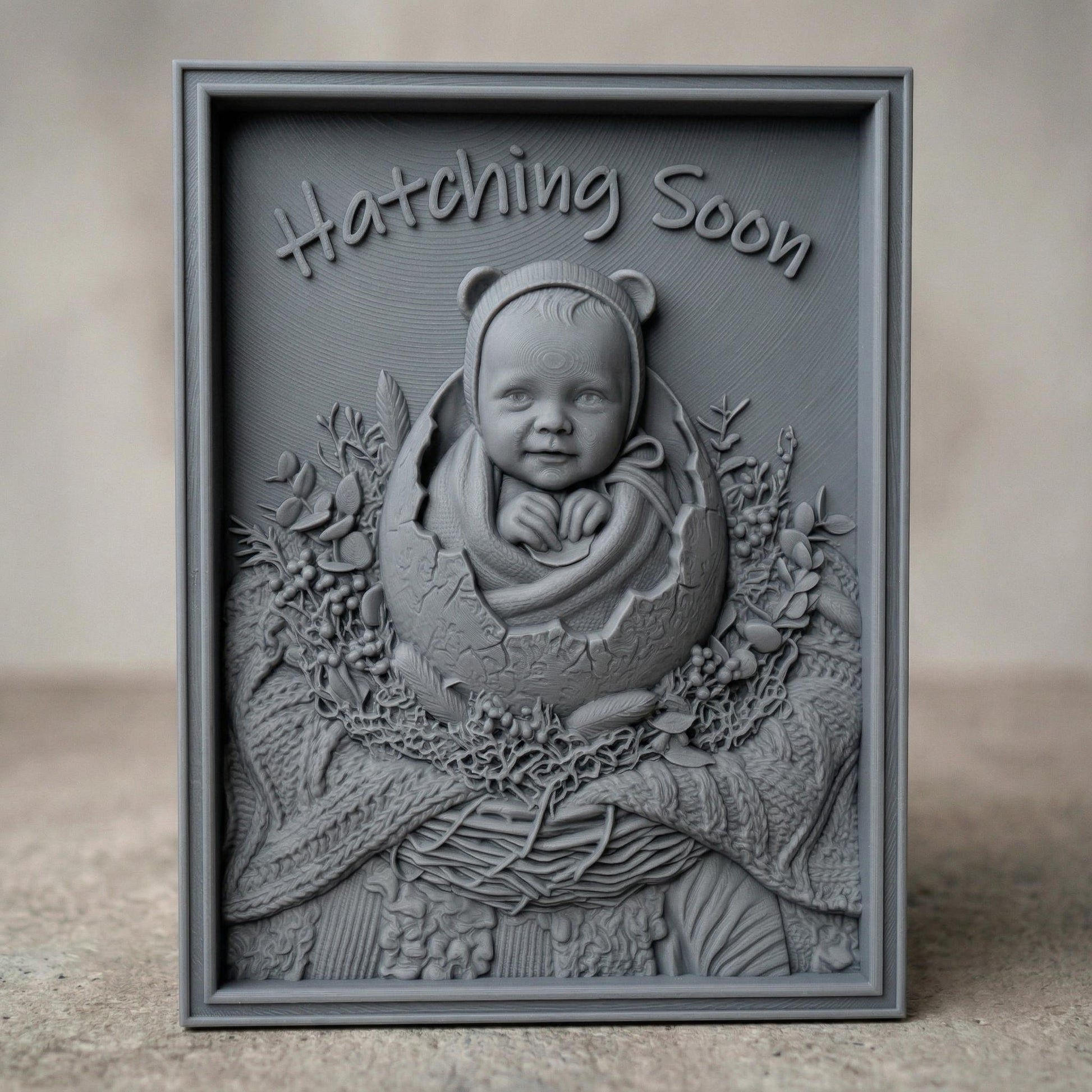 Highly detailed bas-relief carving of a smiling baby emerging from a cracked egg, surrounded by a woven nest and delicate foliage. The phrase “Hatching Soon” arches above, symbolizing anticipation and new life. Soft textures and layered wood grain create a warm, nurturing scene ideal for nursery decor or pregnancy announcements.