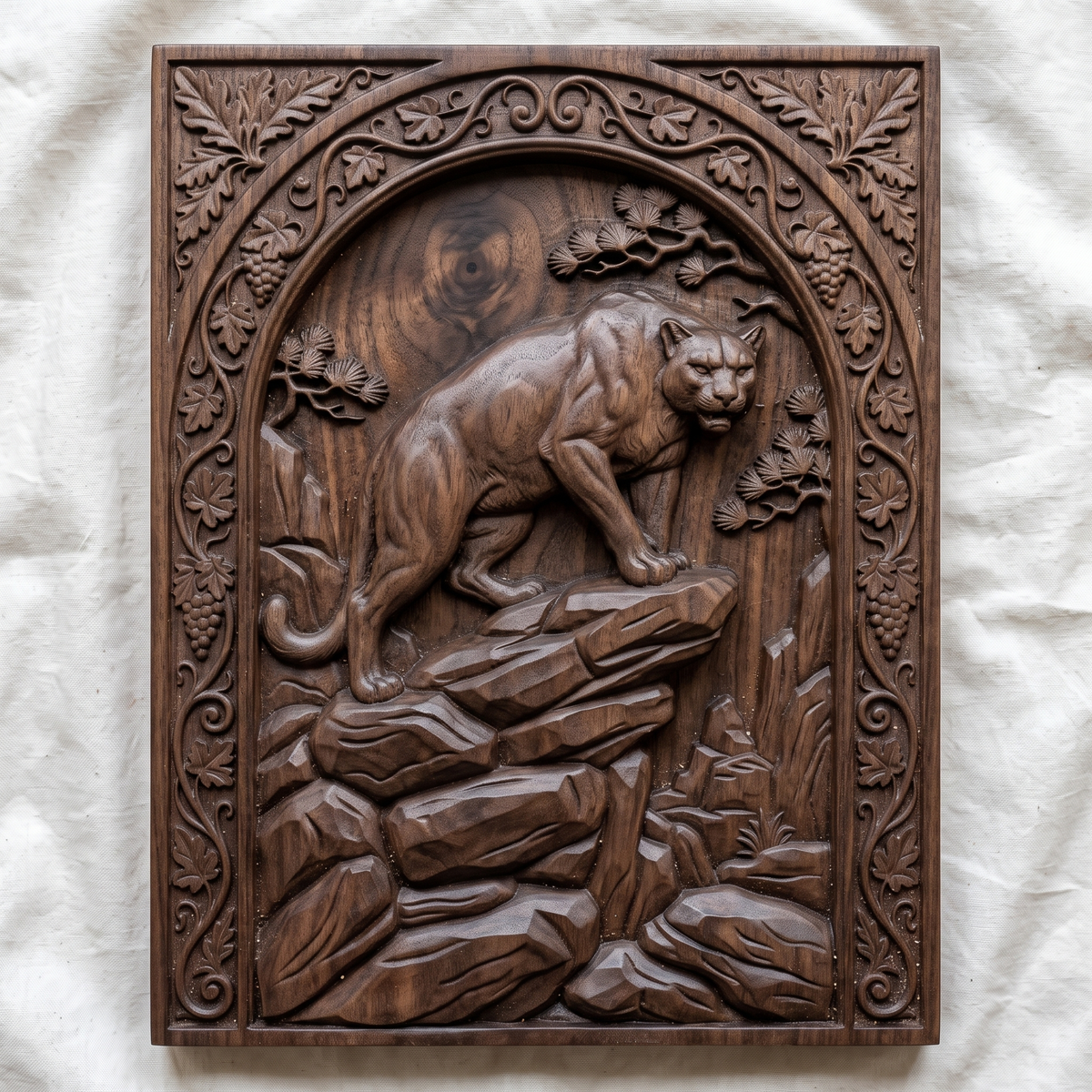 Mountain lion carved in dark walnut wood on a rocky ledge inside an arched rectangular frame with oak leaf, grape vine and pine details, shown as a workshop mockup and a grey resin render. Digital STL relief file for CNC routers and 3D printers, ideal for wildlife wall art, panels and woodworking projects.