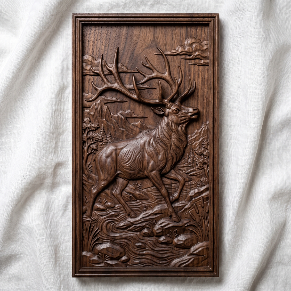 Detailed 3D bas-relief of a majestic bull elk with large antlers raised, striding through a mountain river valley with pine trees, cattails, rocks and clouds, set inside a stepped molded rectangular frame. Shown in carved walnut wood and grey resin. Designed for CNC relief carving, woodworking and 3D printing as rustic wildlife wall decor.