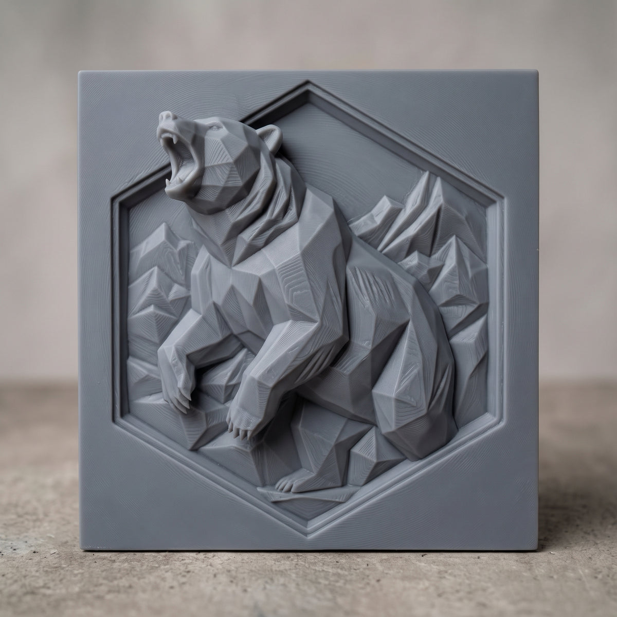 Geometric low poly 3D bas-relief of a roaring bear rearing up with raised front paws, faceted fur and angular mountain peaks. Set inside a recessed hexagon panel on a flat square slab. Shown in carved walnut wood and grey resin. Designed for CNC relief carving, woodworking and 3D printing as modern wildlife and cabin wall decor.