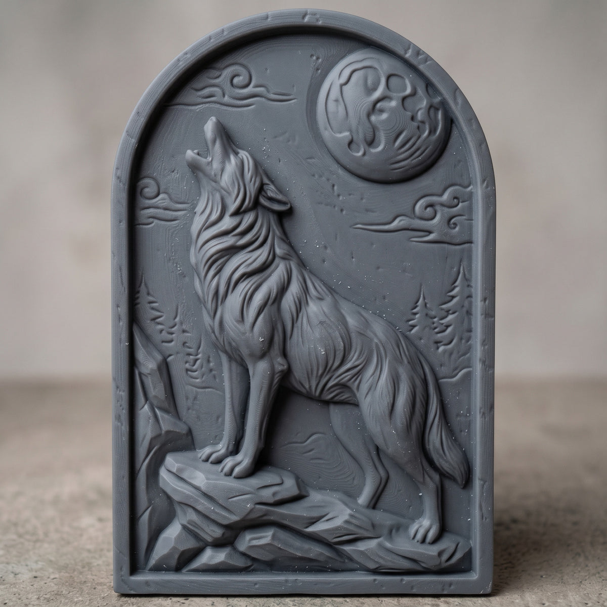 Detailed 3D bas-relief of a wolf howling at a full moon, standing on a rocky ledge with deep fur texture, swirling clouds, pine trees and mountain rocks behind. The scene is carved on an arched-top panel with a thin raised border and rustic wood grain. Designed for CNC router carving, wood routing and 3D printing as wolf wall decor for a cabin or lodge.